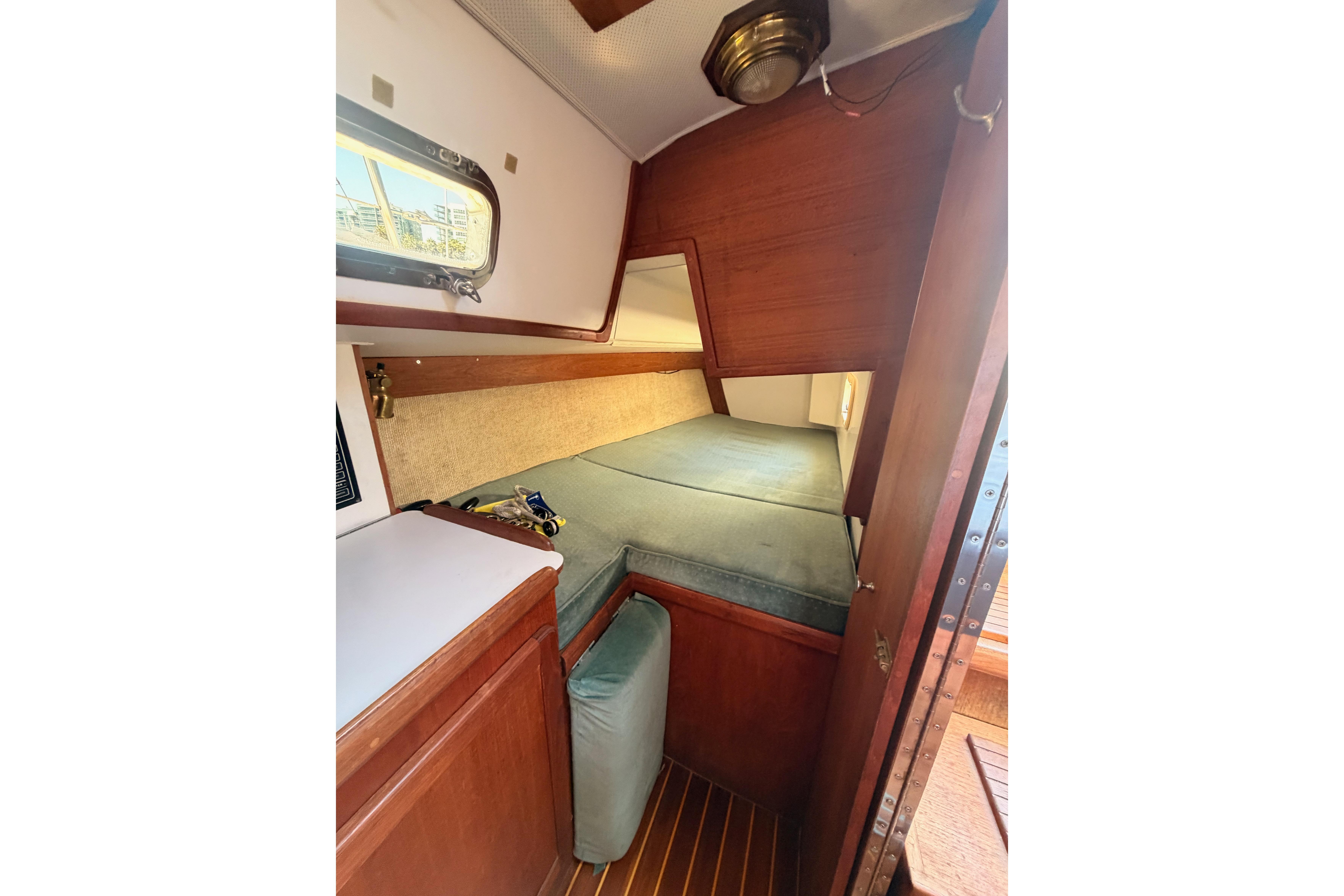 Cozy cabin interior of 1991 Caliber 33 sailboat with wooden finish and cushioned bed.