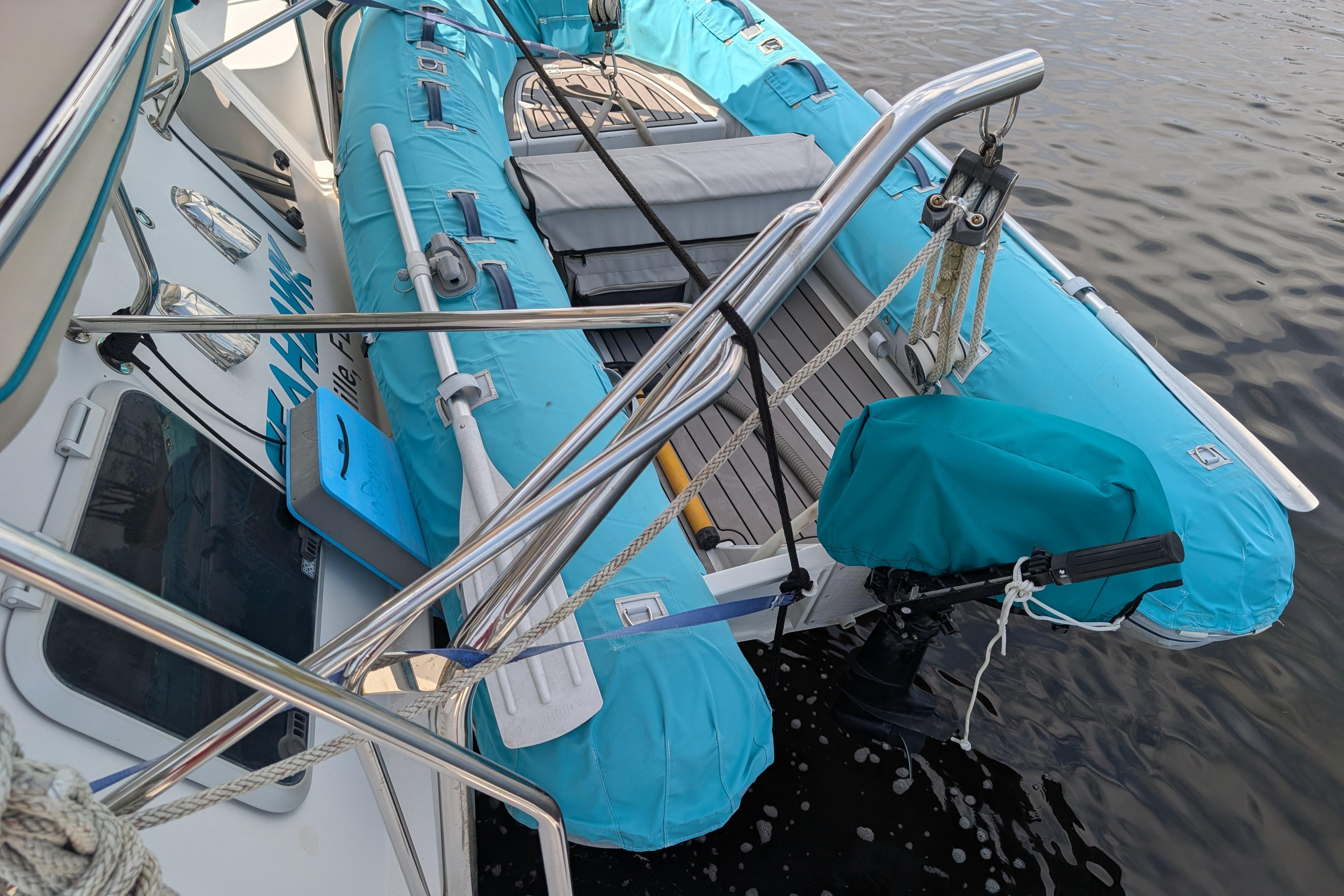 2004 PDQ 34 Powercat with blue inflatable dinghy secured on deck.