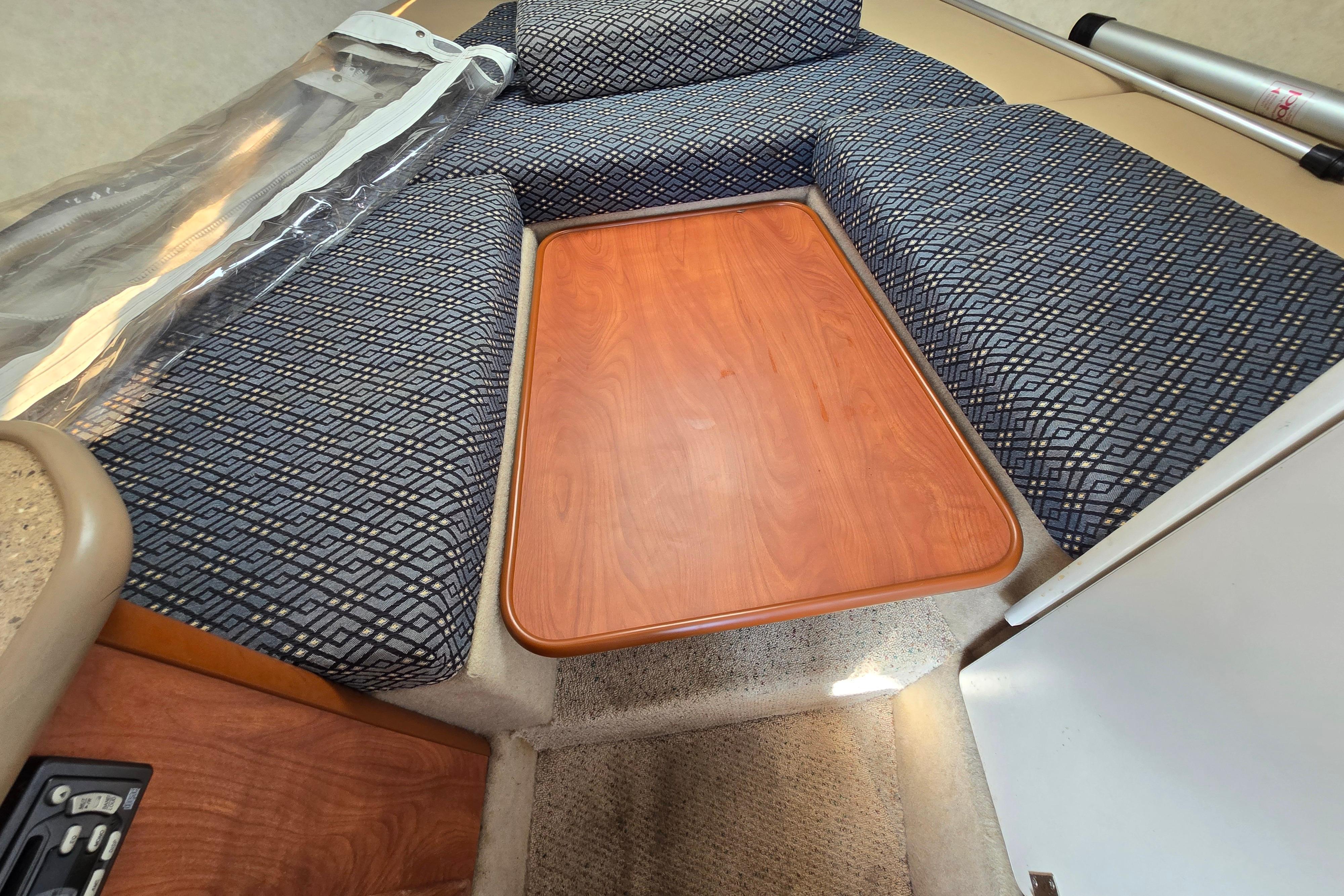 2006 Bayliner 222 Classic cabin interior with patterned seating and wooden table.