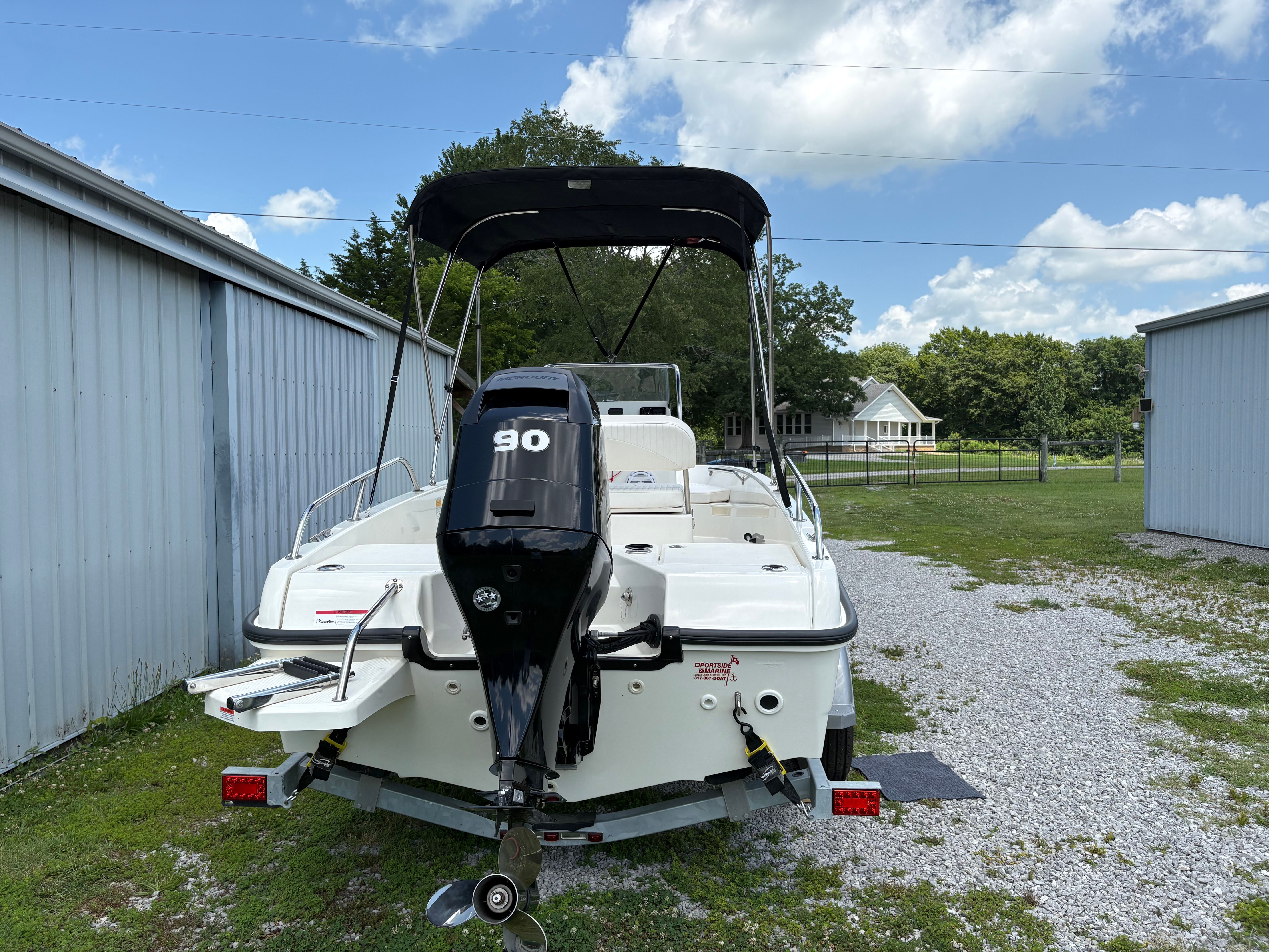 A 2013 Boston Whaler 170 Dauntless on a trailer, surrounded by buildings and trees.
