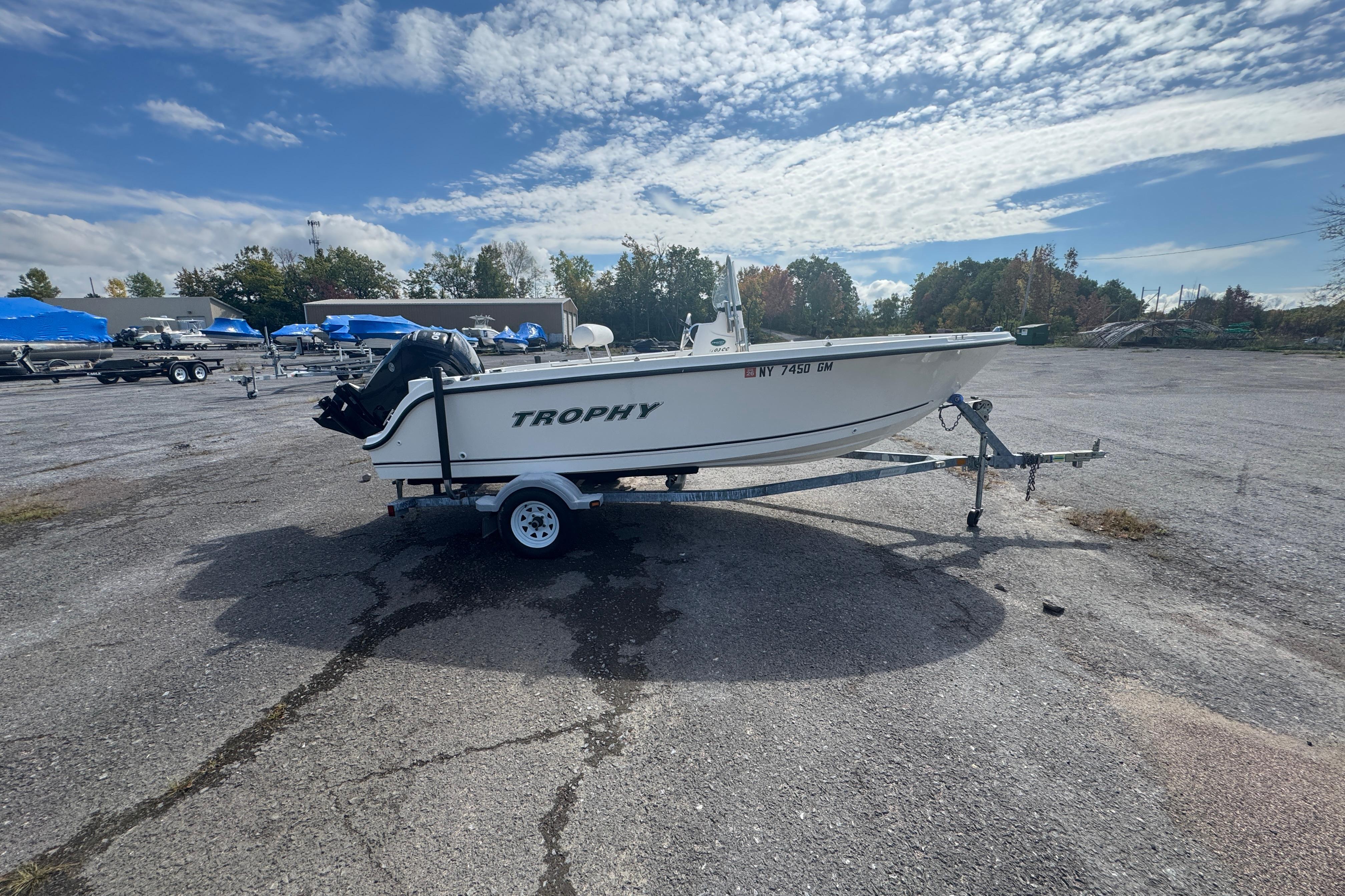 2007 Trophy 1703 Center Console boat on trailer in parking lot under cloudy sky.