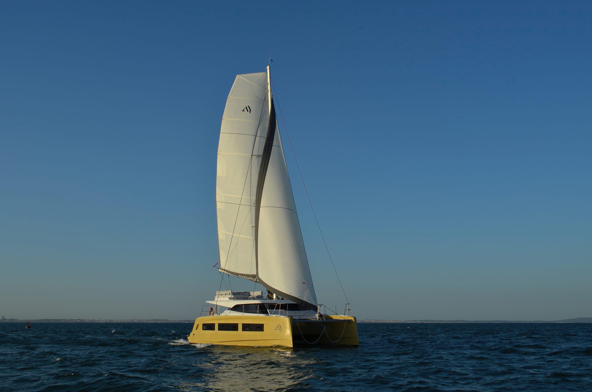 Aventura 45 catamaran sailing on open sea under clear blue sky, 2026 model.