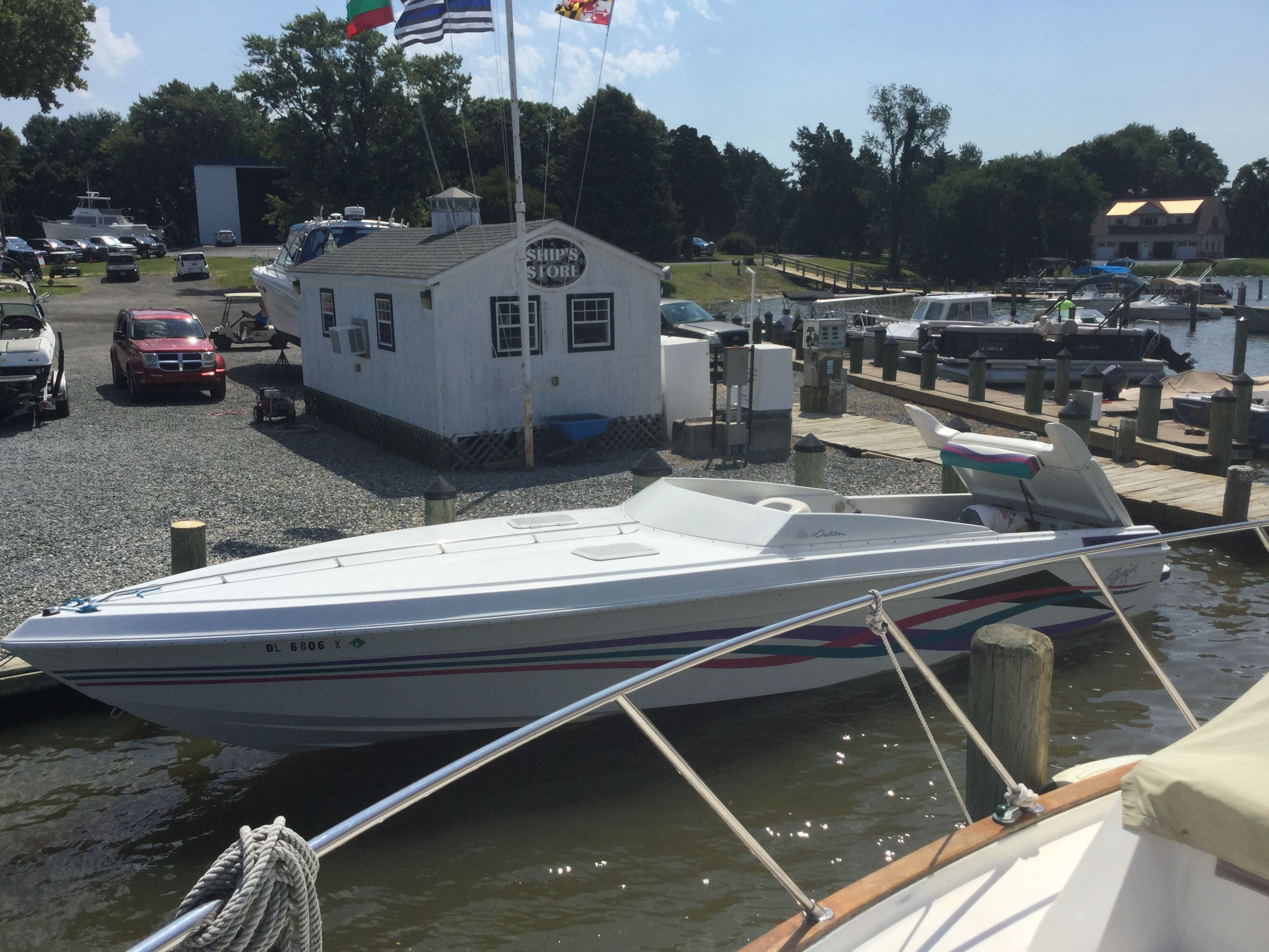 A 1995 Baja Caliber is docked at a marina, surrounded by boats and a shop.