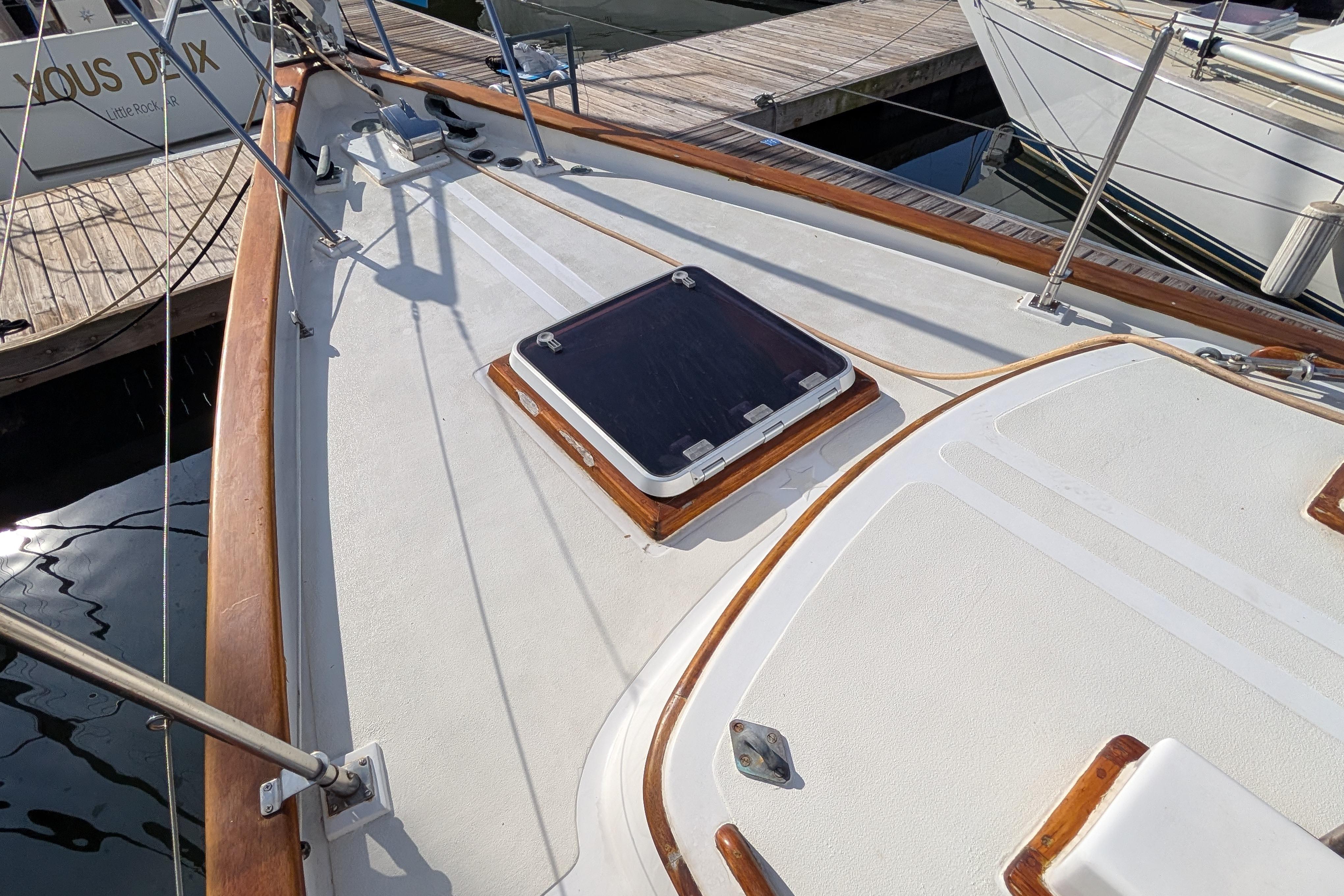 Deck of a 1983 Robert Perry 41 sailboat with wooden trim and hatch.