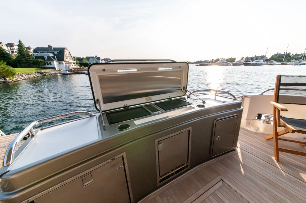 2022 Riviera 6000 Sport Yacht Platinum with outdoor kitchen, docked by waterfront homes.