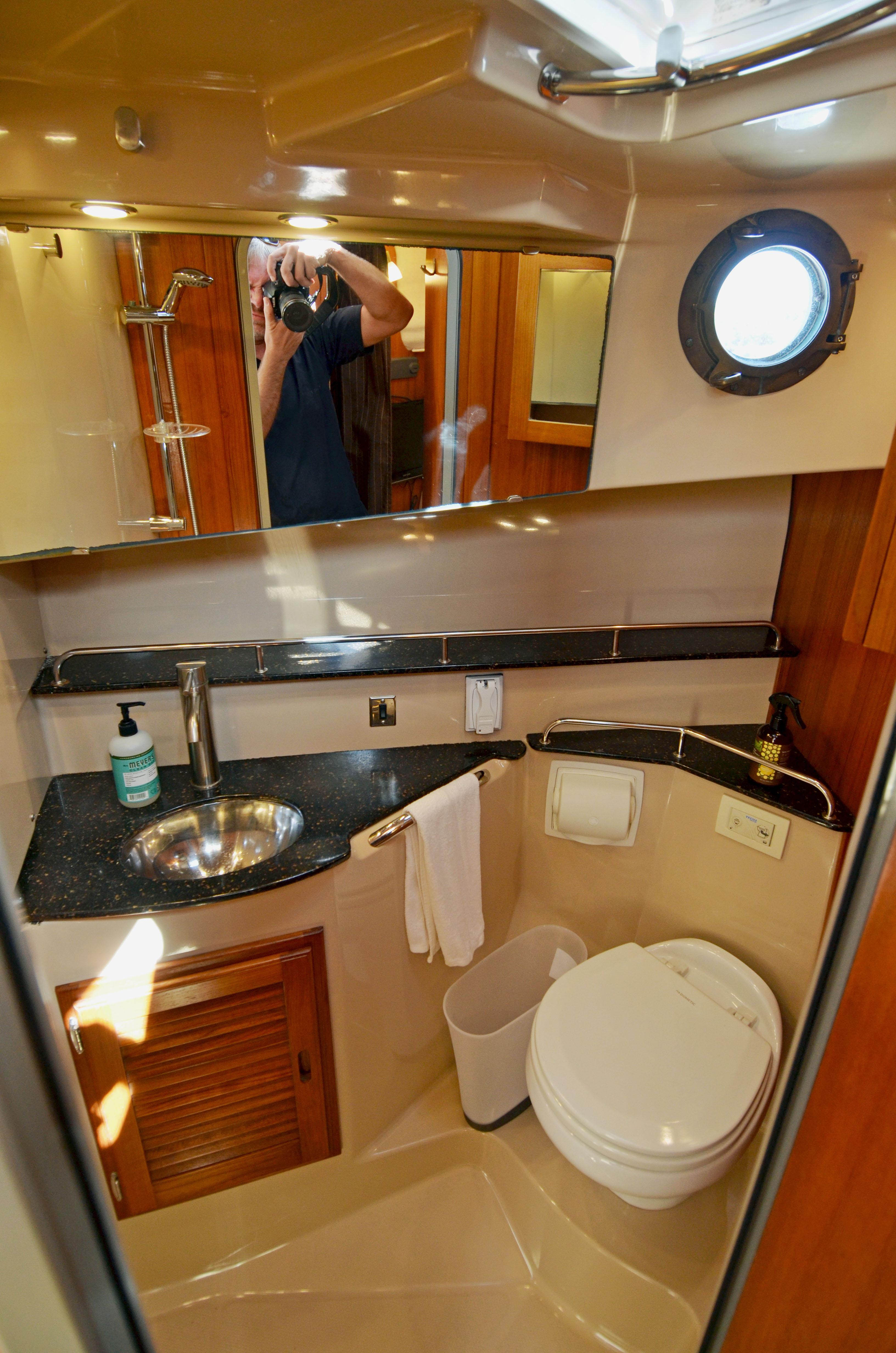 2013 Ranger Tugs R-31 CB bathroom with sink, toilet, and porthole window.