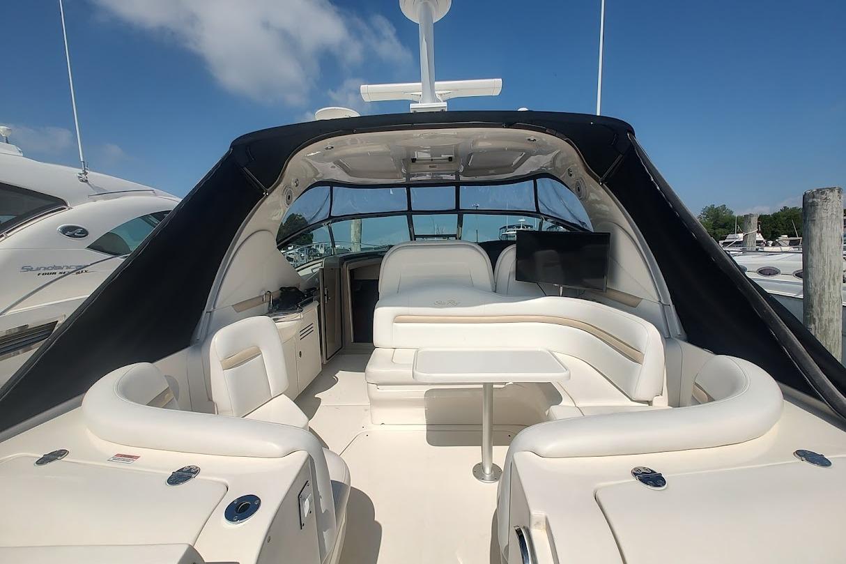 2009 Sea Ray 380 Sundancer yacht interior with white seating and table under blue sky.