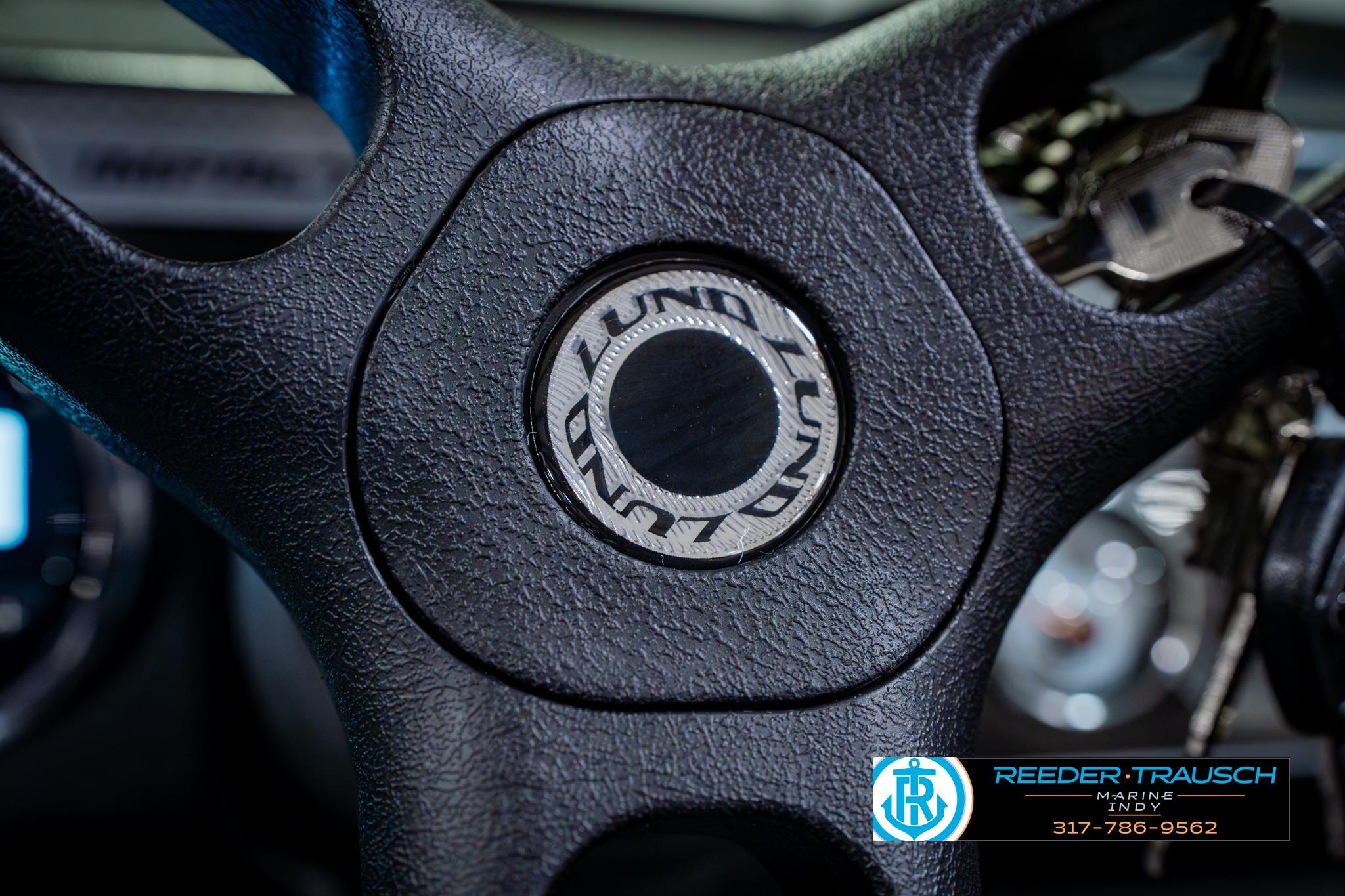 Steering wheel of 2026 Lund 1875 Impact XS boat with logo detail.