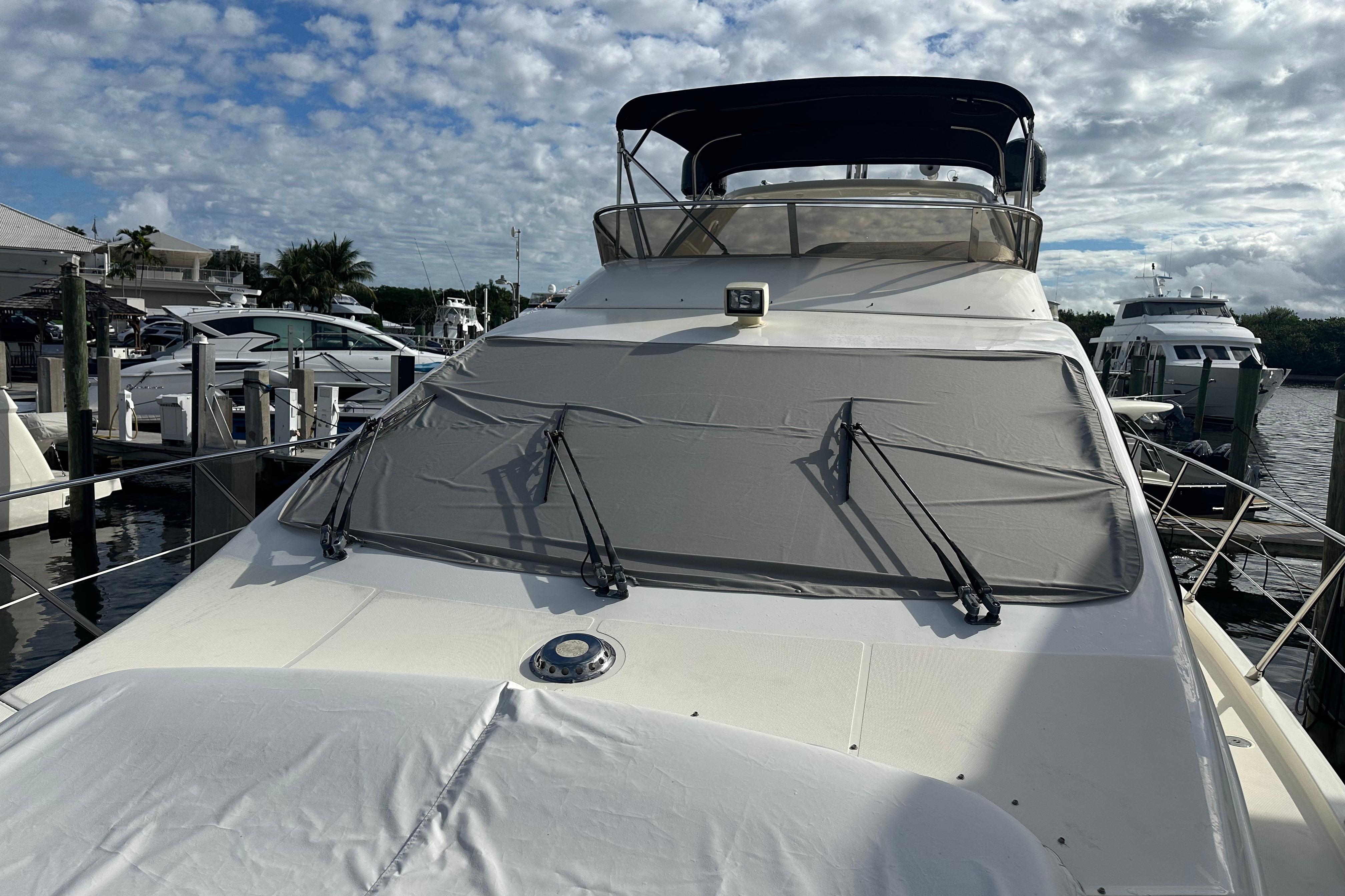 2004 Azimut 55E yacht docked at marina under partly cloudy sky.