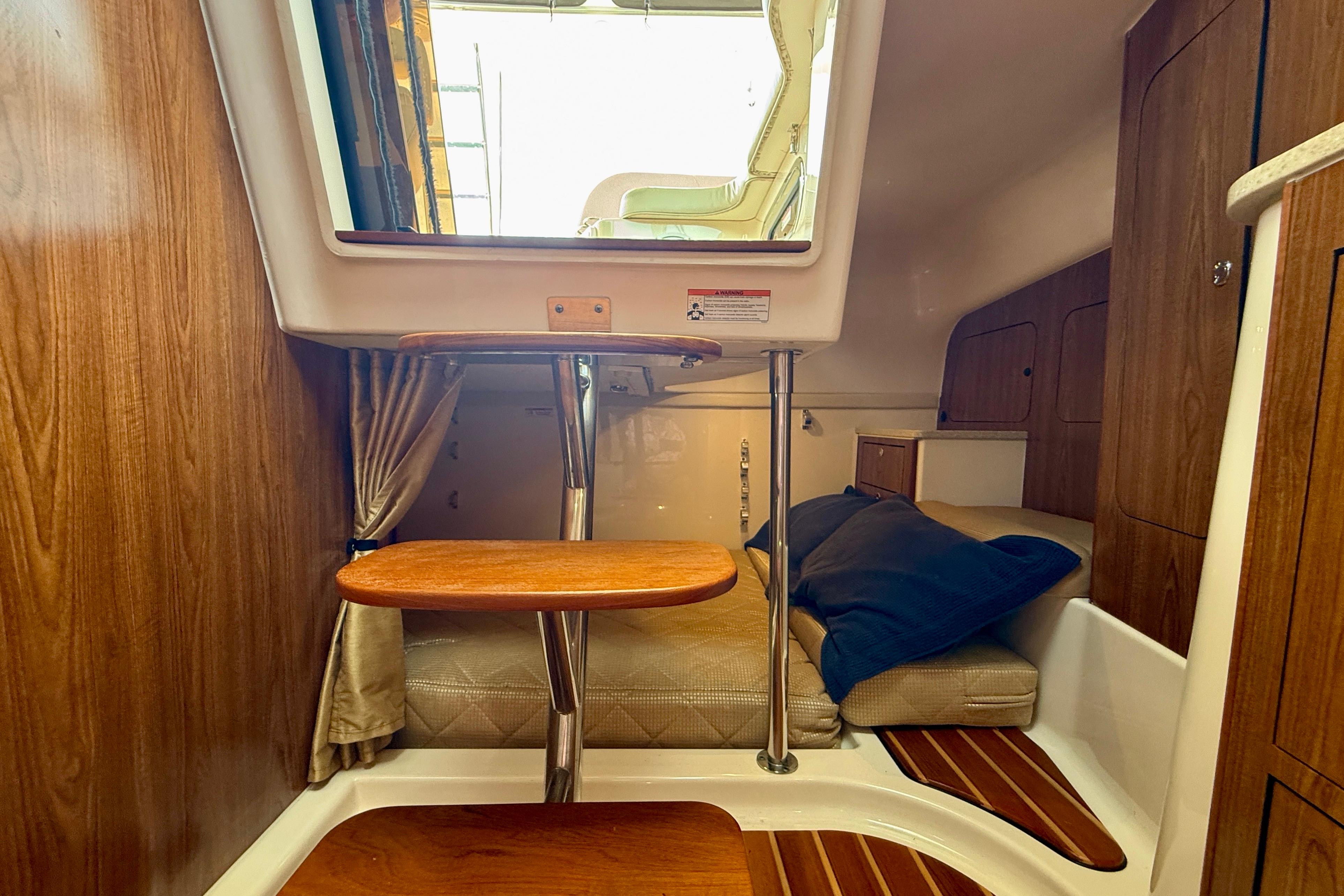 Interior cabin of 2012 Pursuit OS 345 Offshore boat with wooden accents and cozy seating.