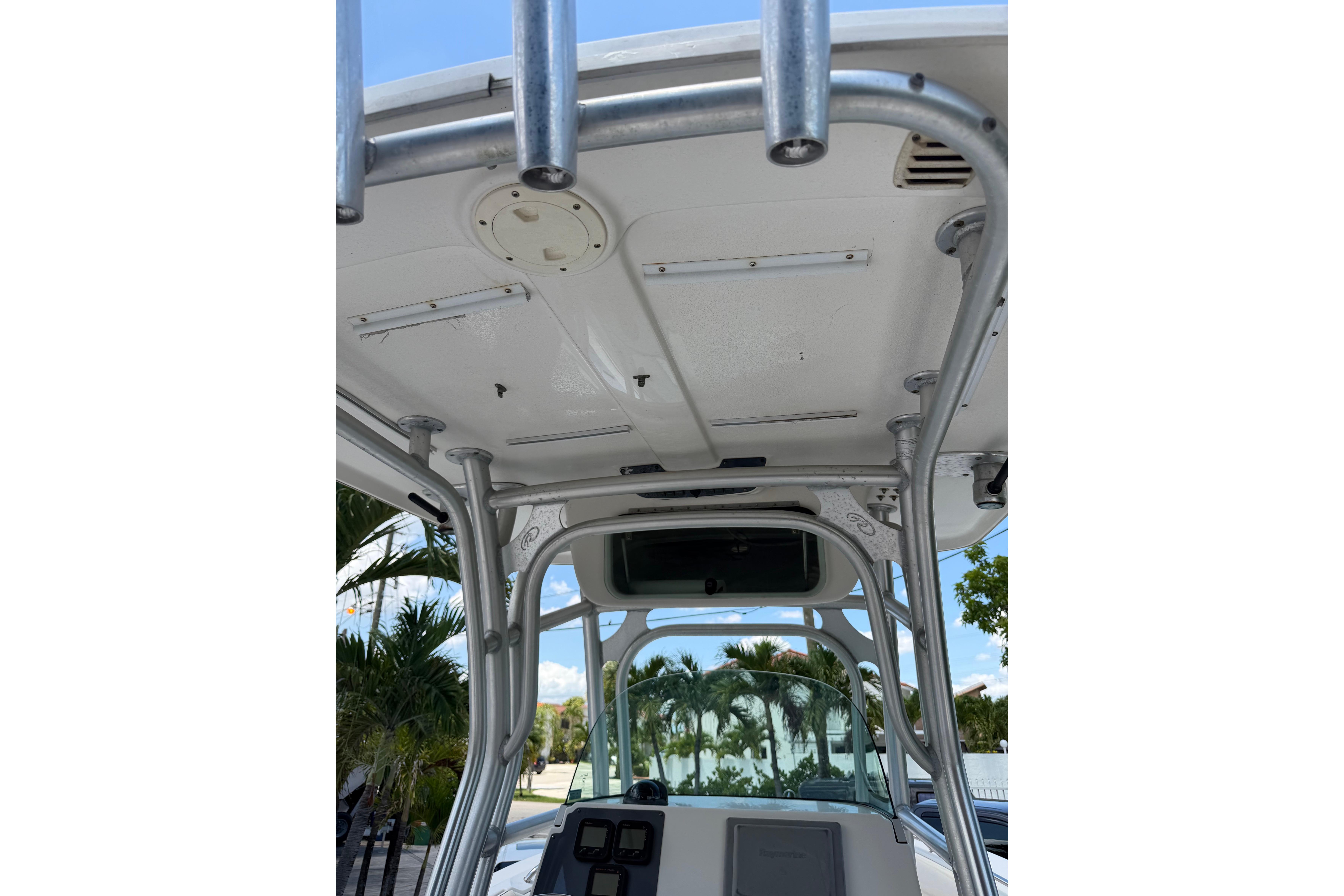 2007 Robalo R260 Center Console boat with T-top and rod holders, docked near palm trees.