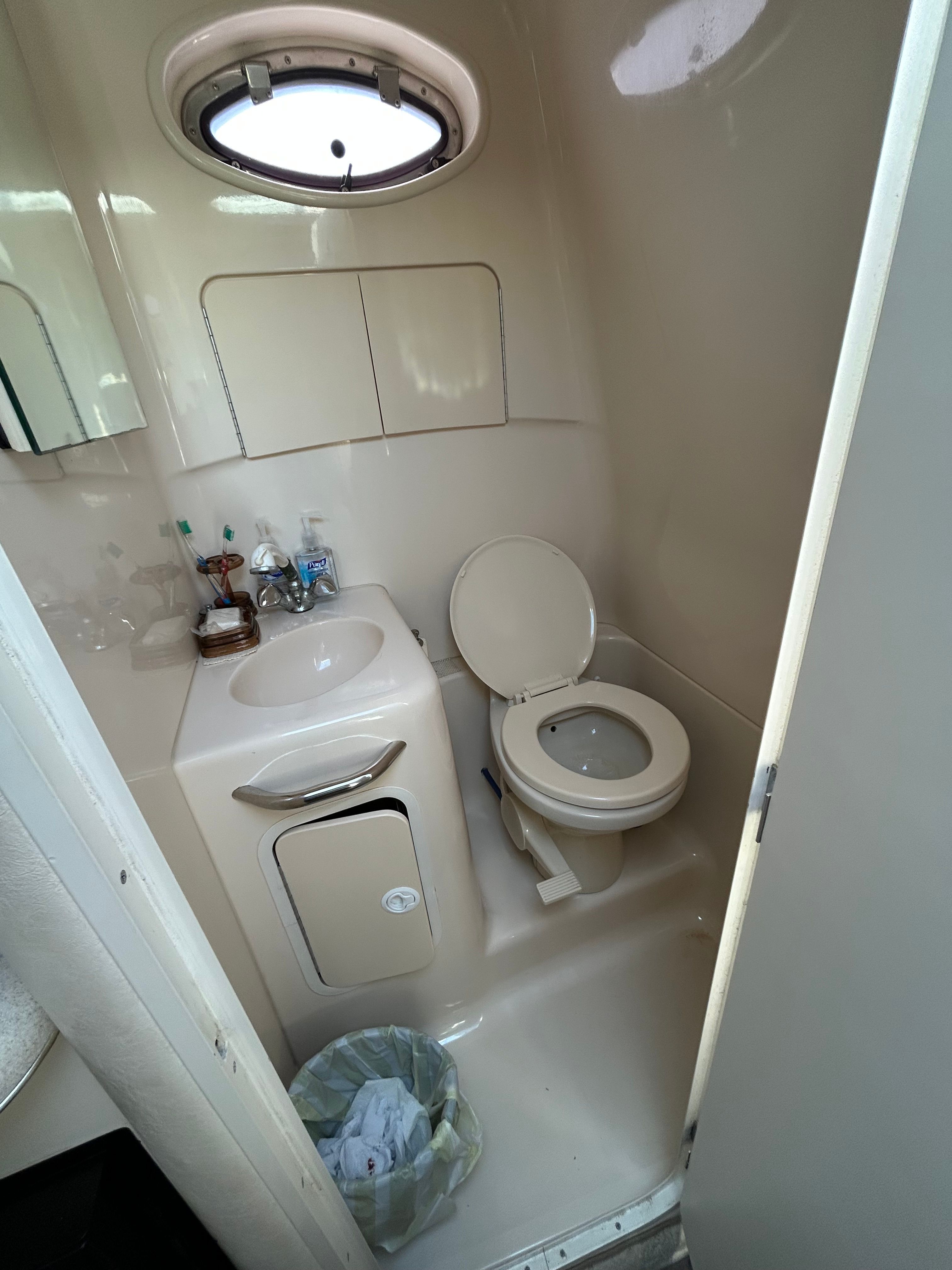 The image shows a boat bathroom with a toilet, sink, and small window.