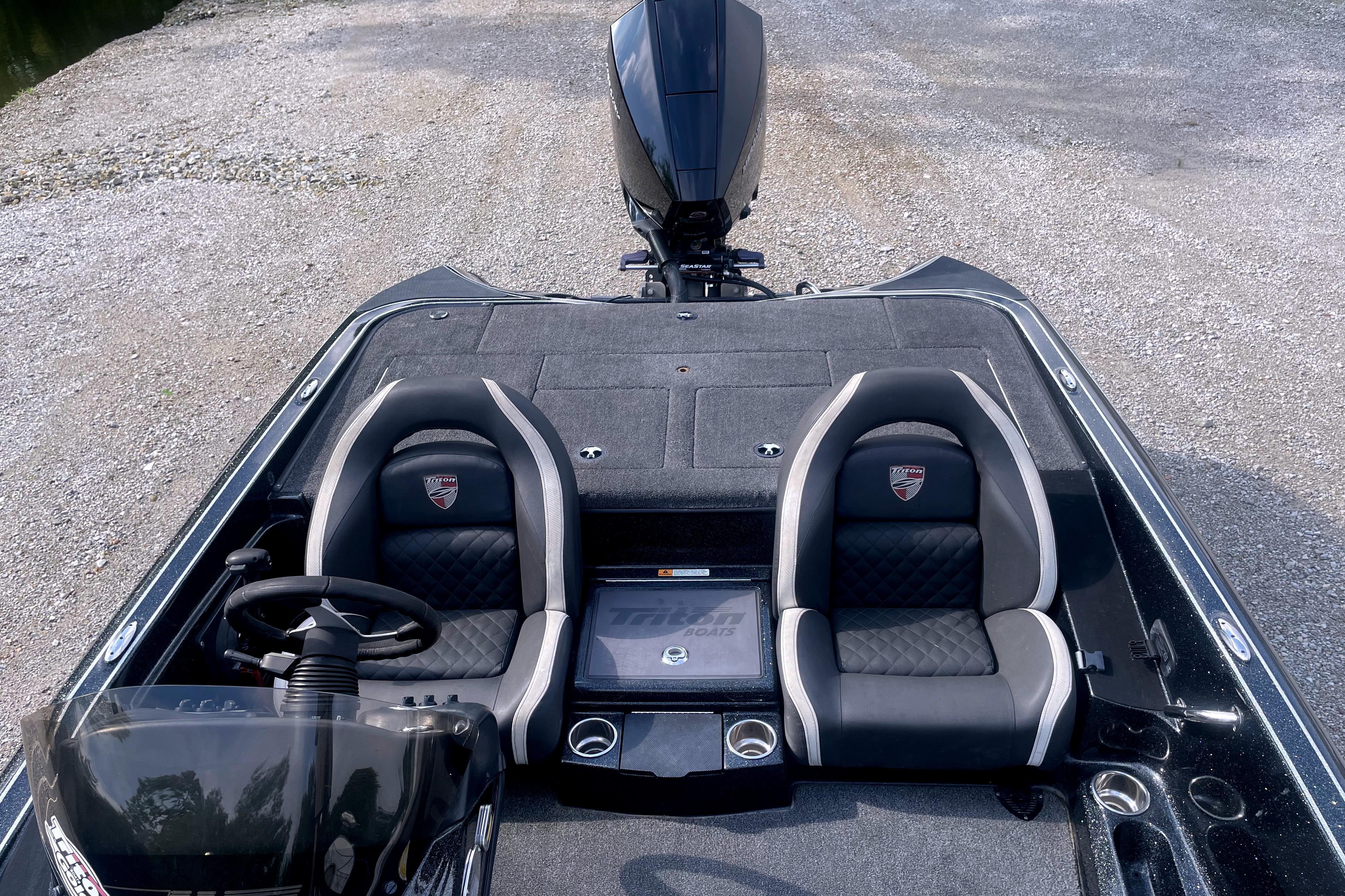 2022 Triton 18 TrX boat interior with dual seats and steering wheel, parked on gravel.