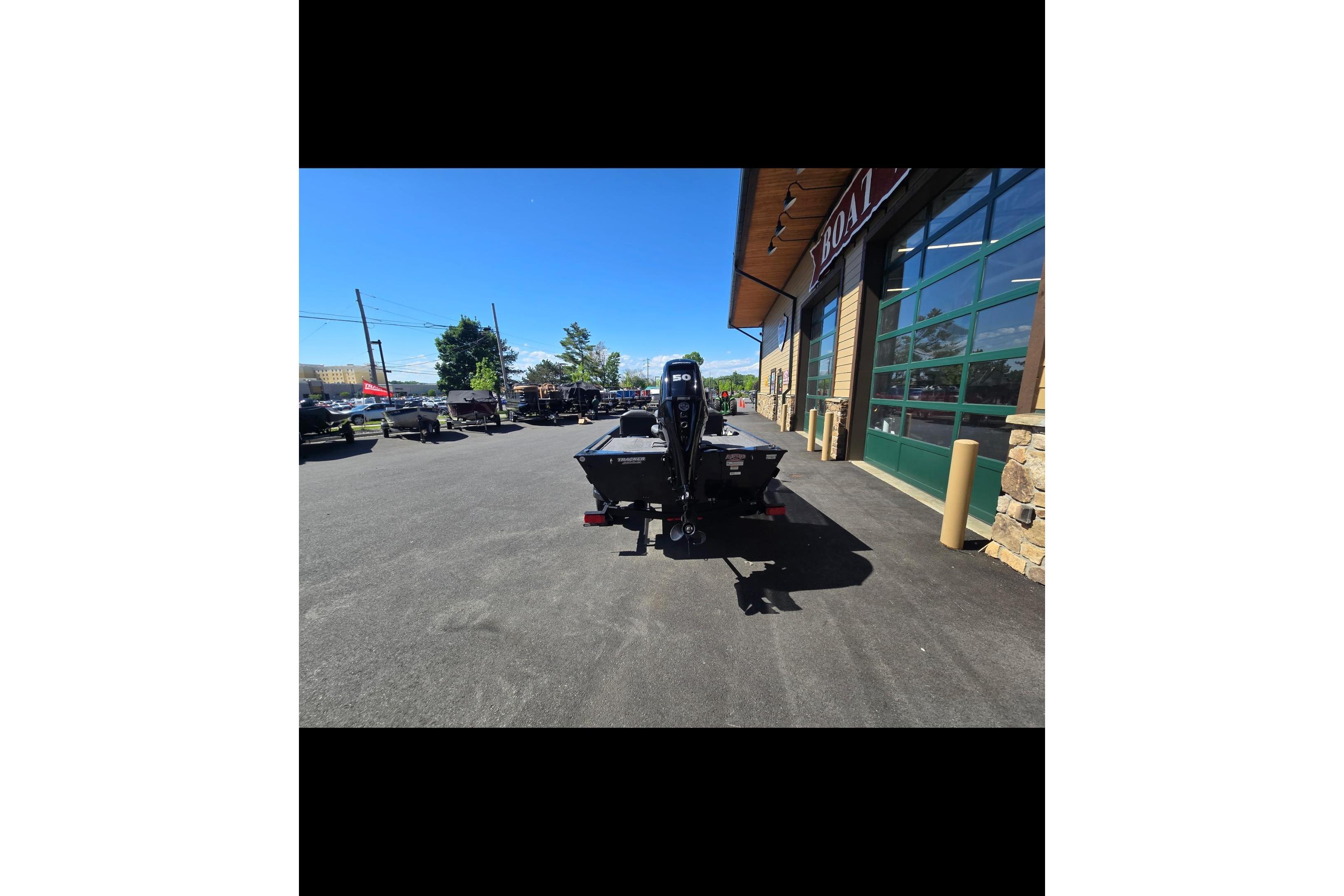 2024 Tracker Bass Tracker Classic XL boat parked outside a store on a sunny day.