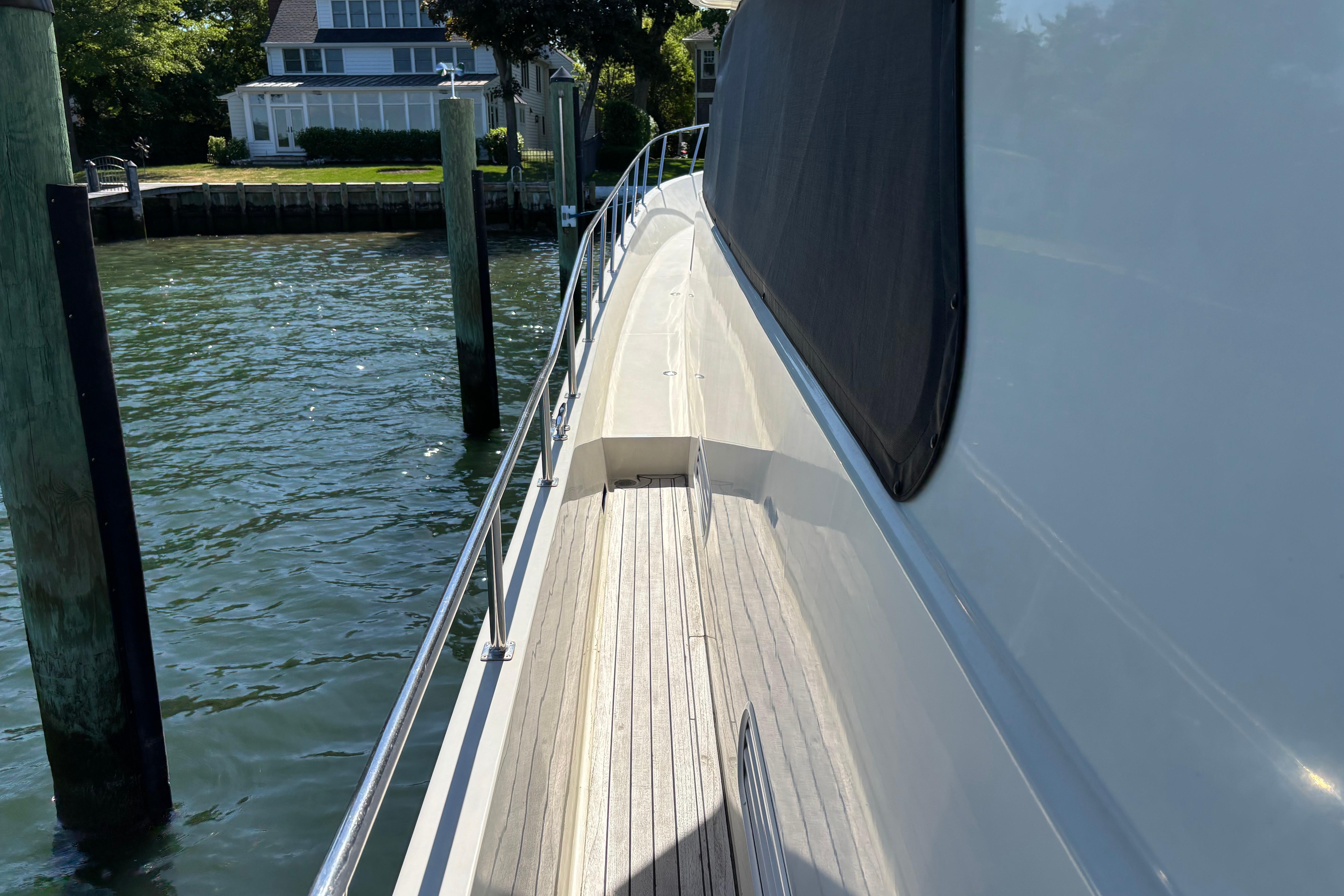 Side view of a 2004 Hampton F/B Cruiser docked by a waterfront home.