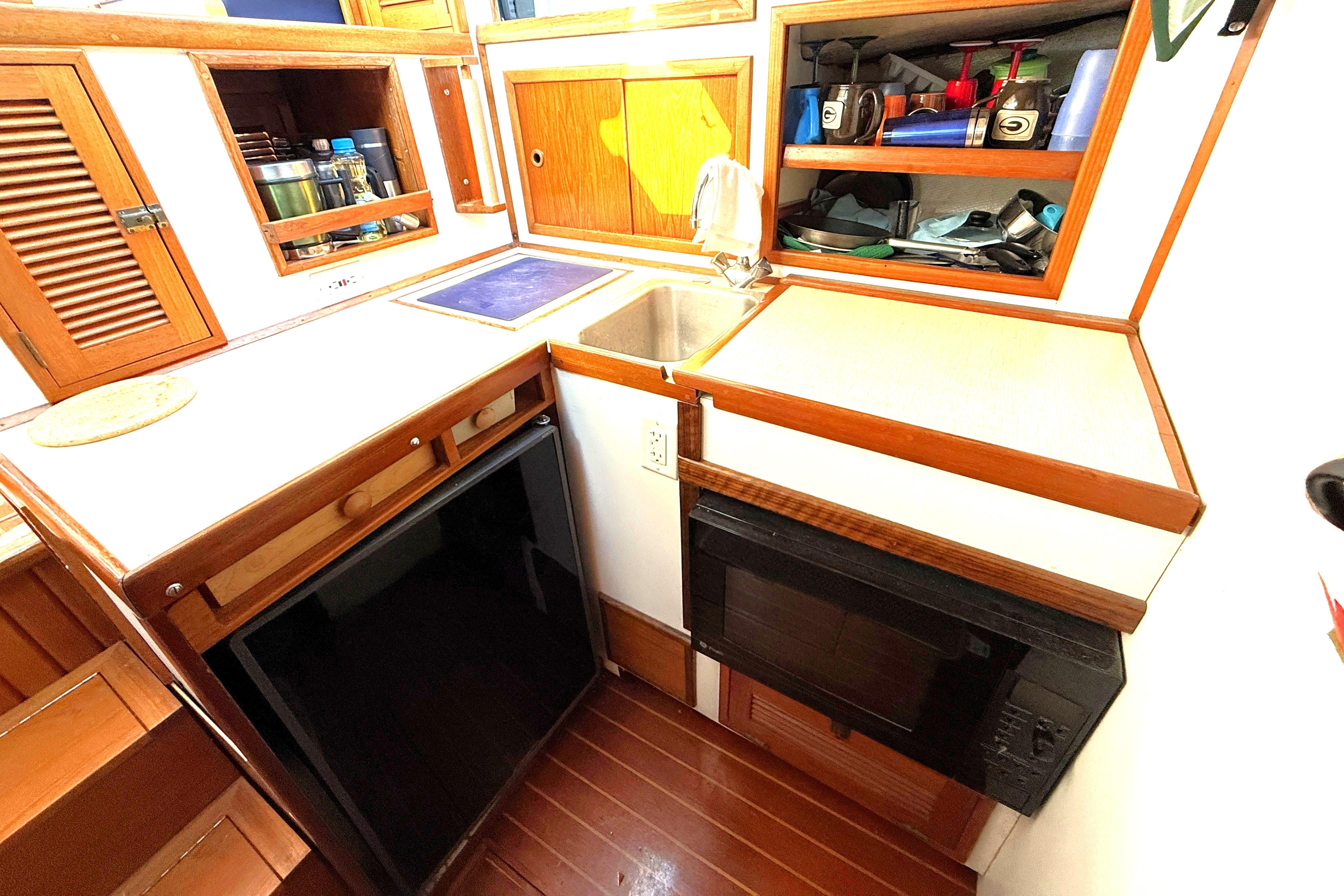1983 Wilbur 34 Fly Bridge Cruiser kitchen with wooden cabinets and compact appliances.