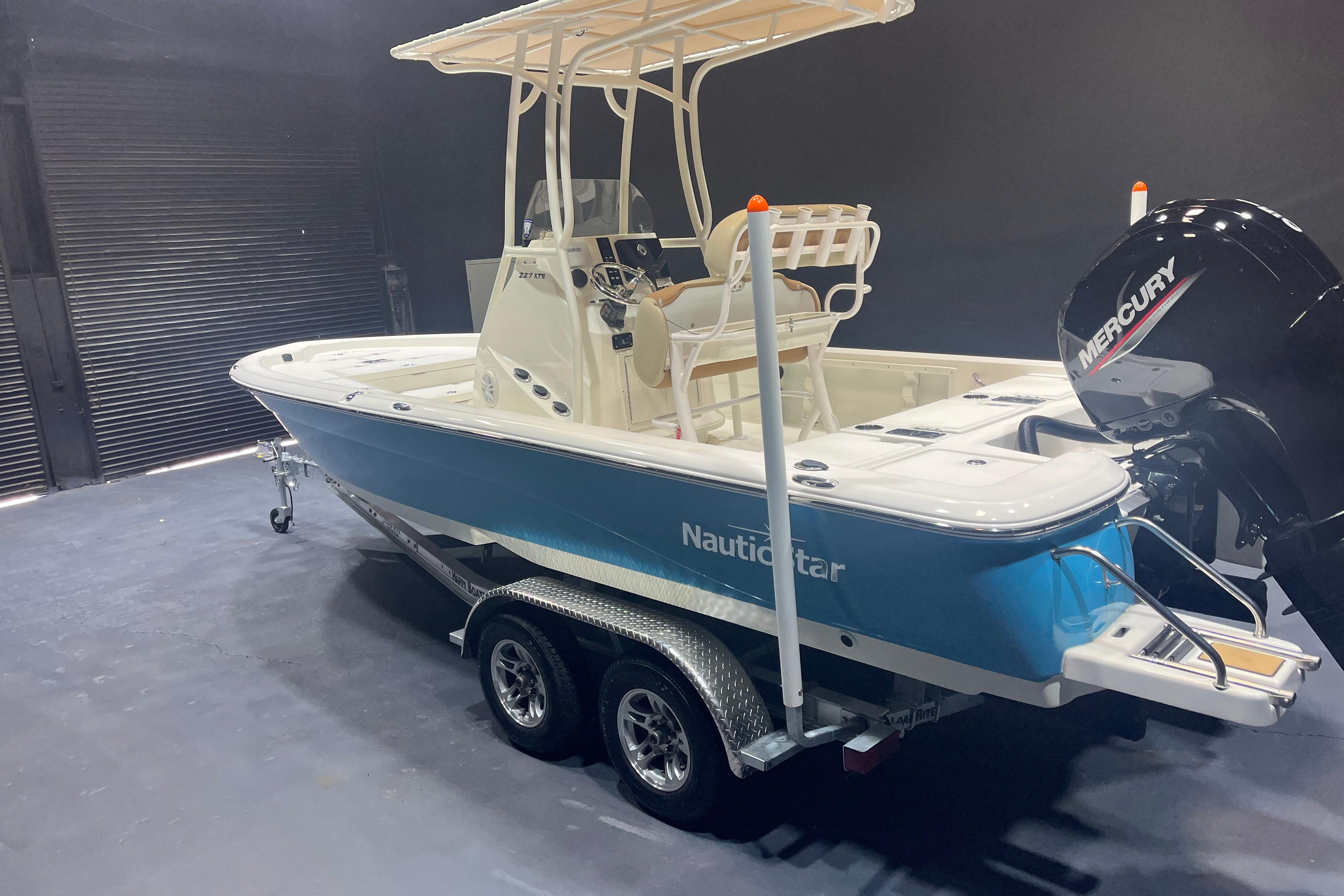 2023 NauticStar 227 XTS boat with Mercury engine on trailer in showroom.