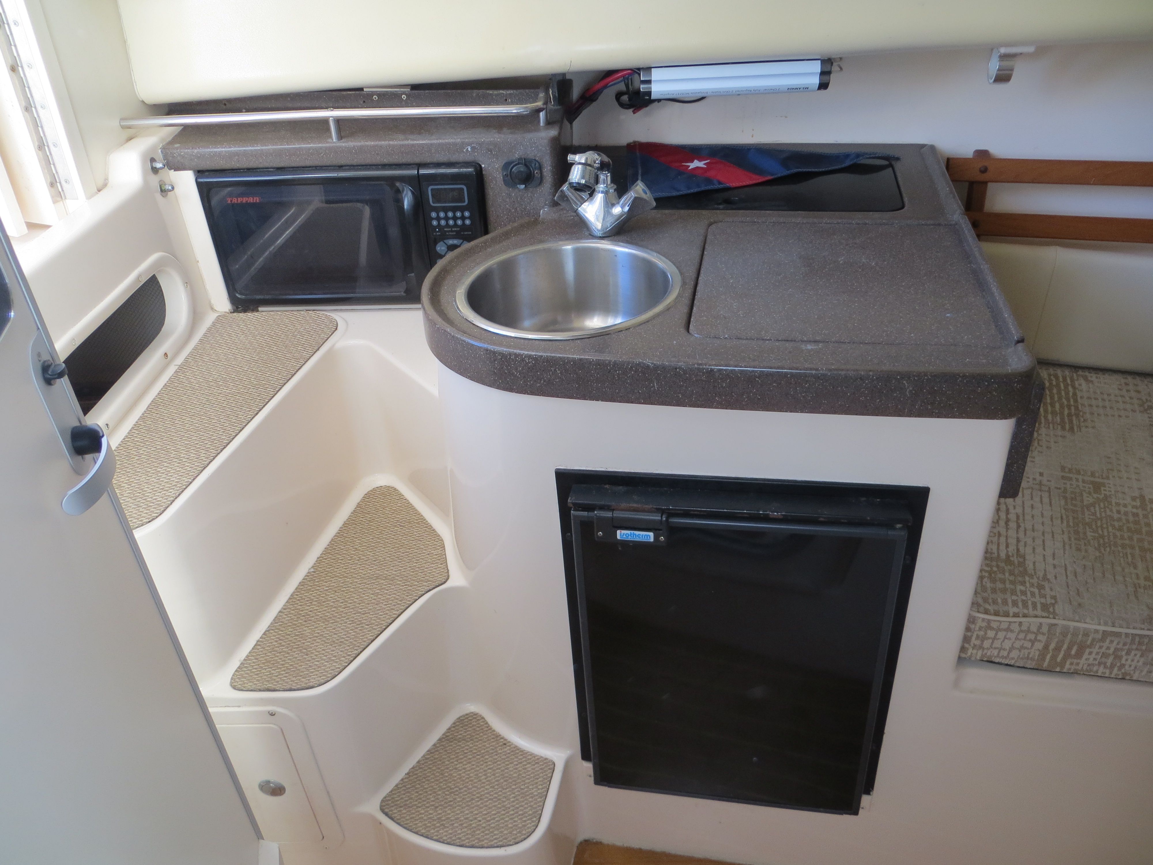The cabin of the 2007 Grady-White Sailfish 282 features a compact kitchen with a sink, microwave, and fridge.