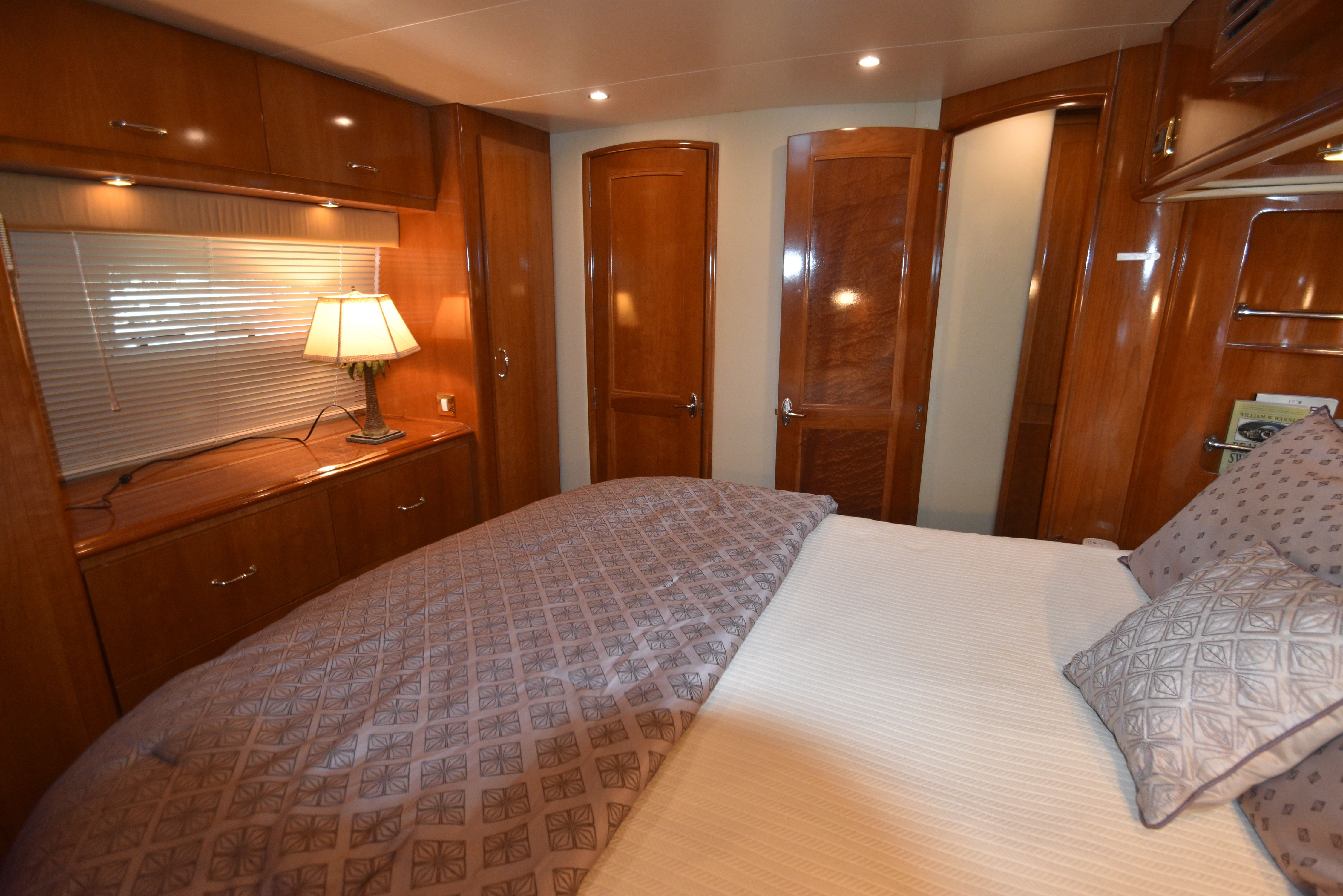 Interior of a luxurious yacht cabin with wooden furnishings and a large bed.