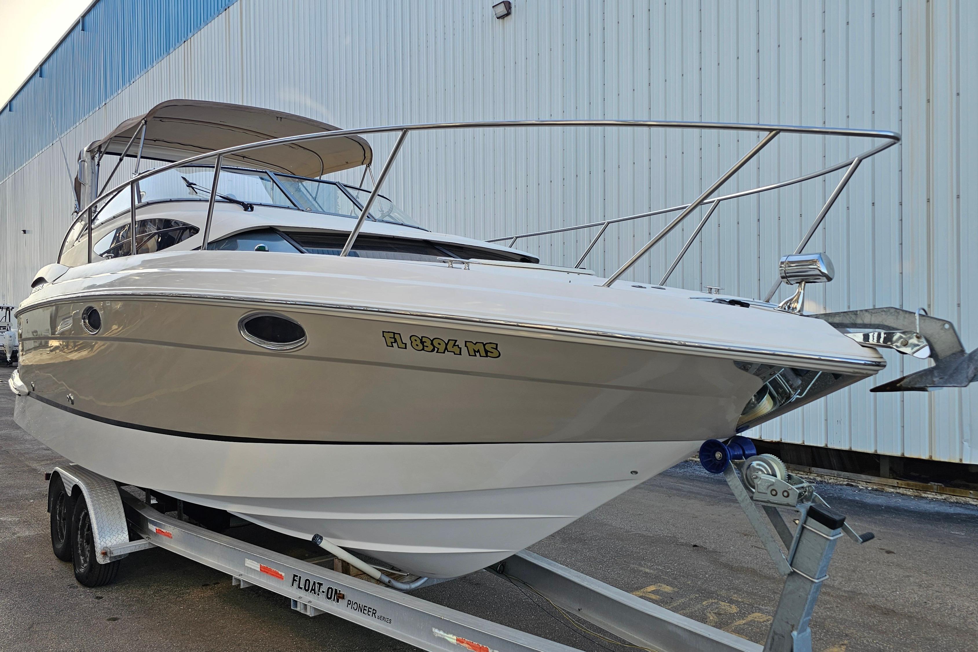 2005 Regal 3060 Window Express boat on trailer, parked near a large building.