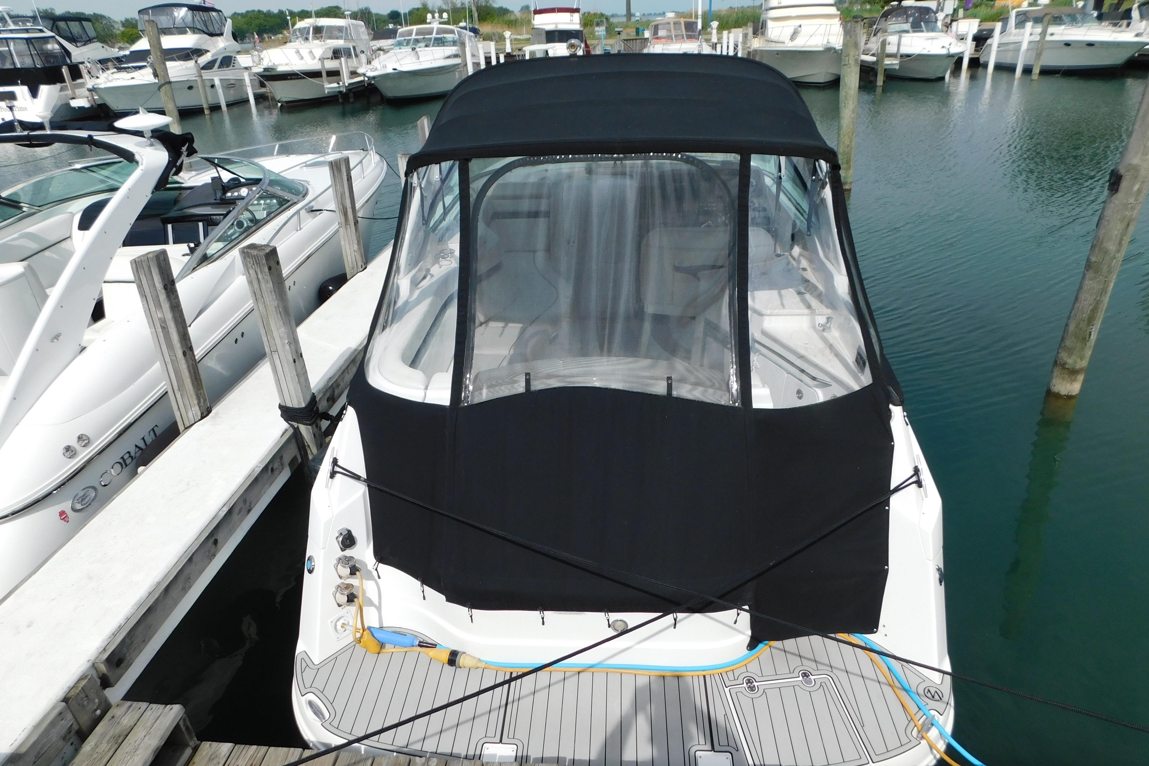 2017 Rinker EX 320 boat docked at marina with black canopy cover.