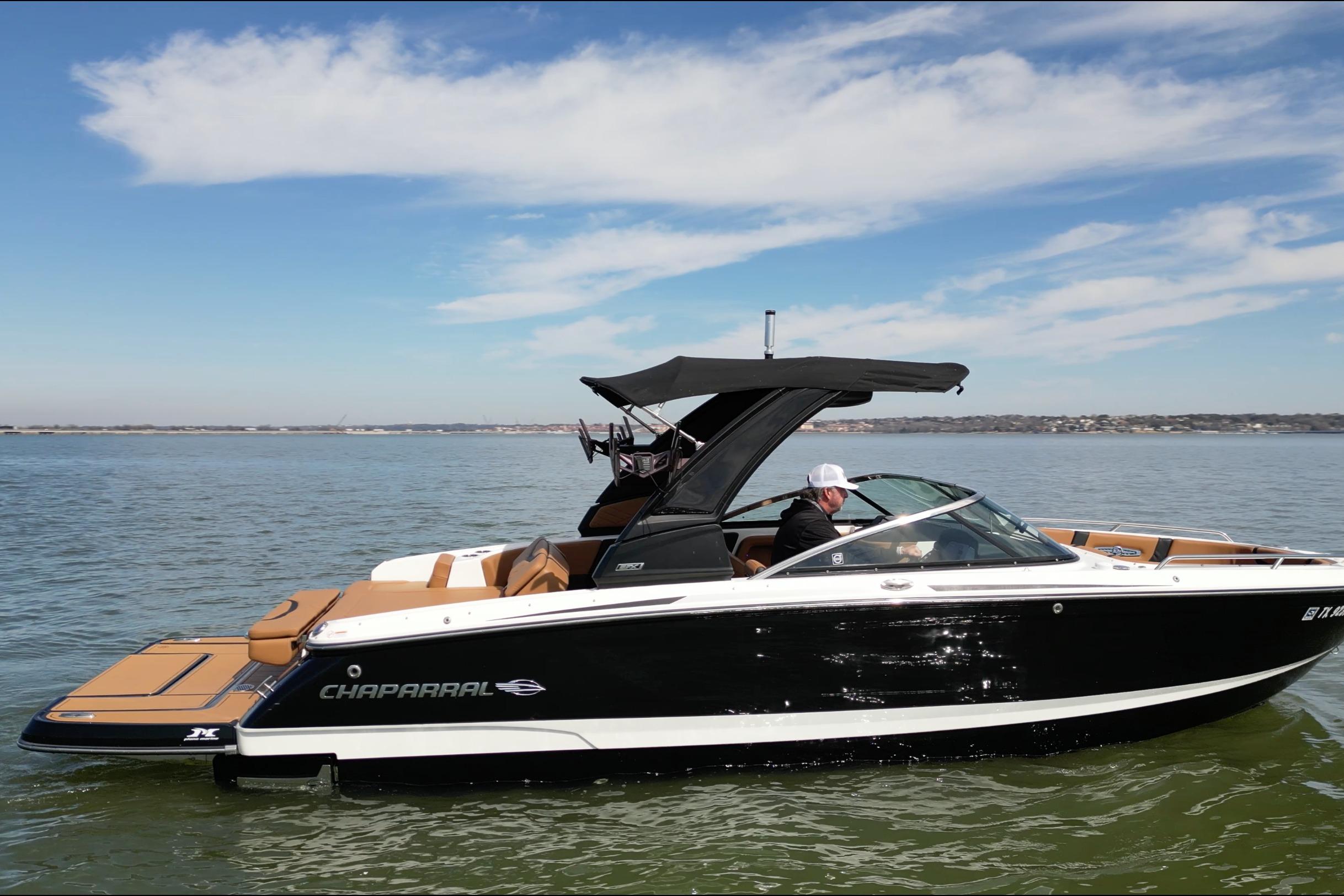 2023 Chaparral 26 Surf boat cruising on a calm lake under a clear sky.