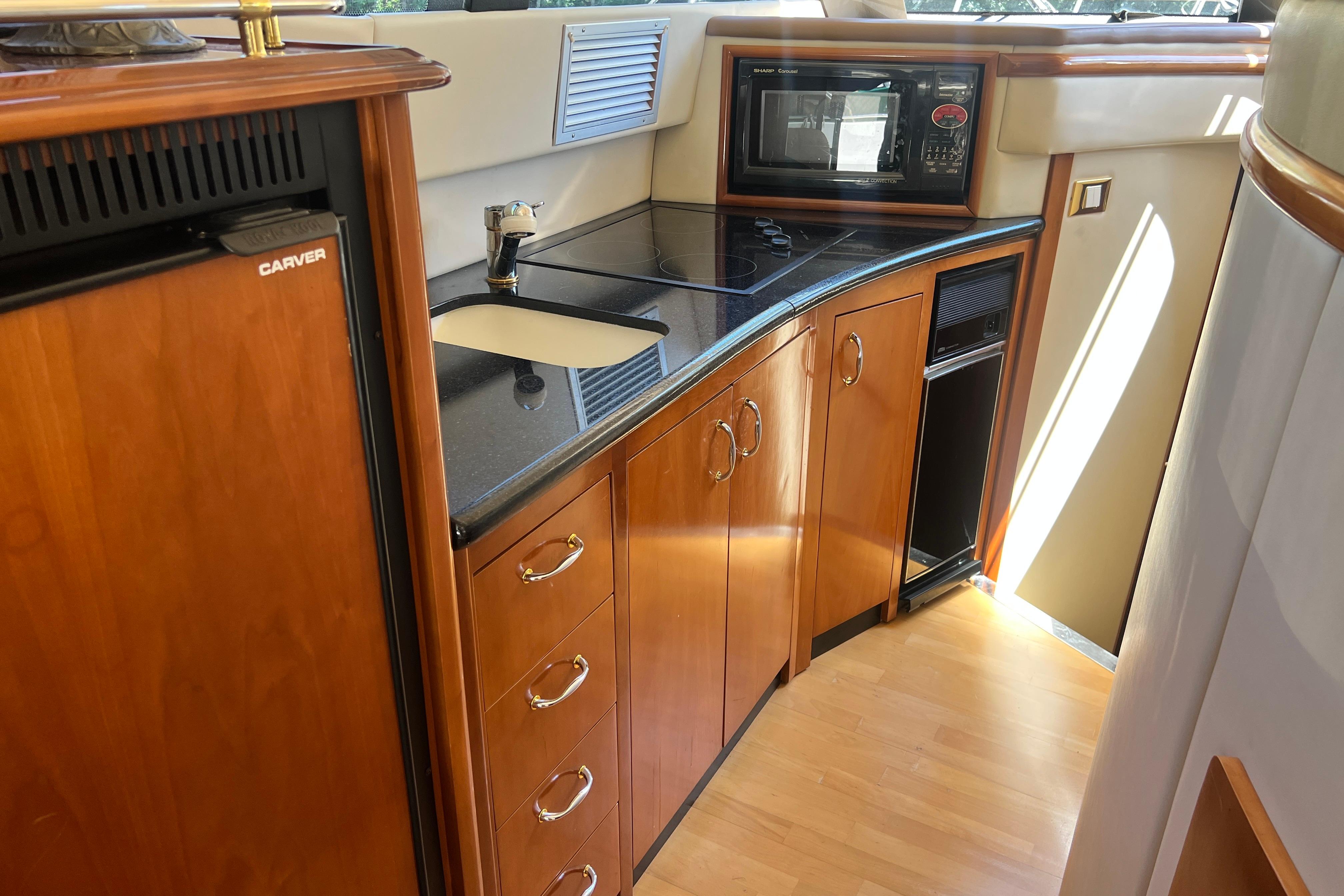 Luxurious 2003 Carver 450 Voyager Pilothouse kitchen with wood cabinetry and modern appliances.