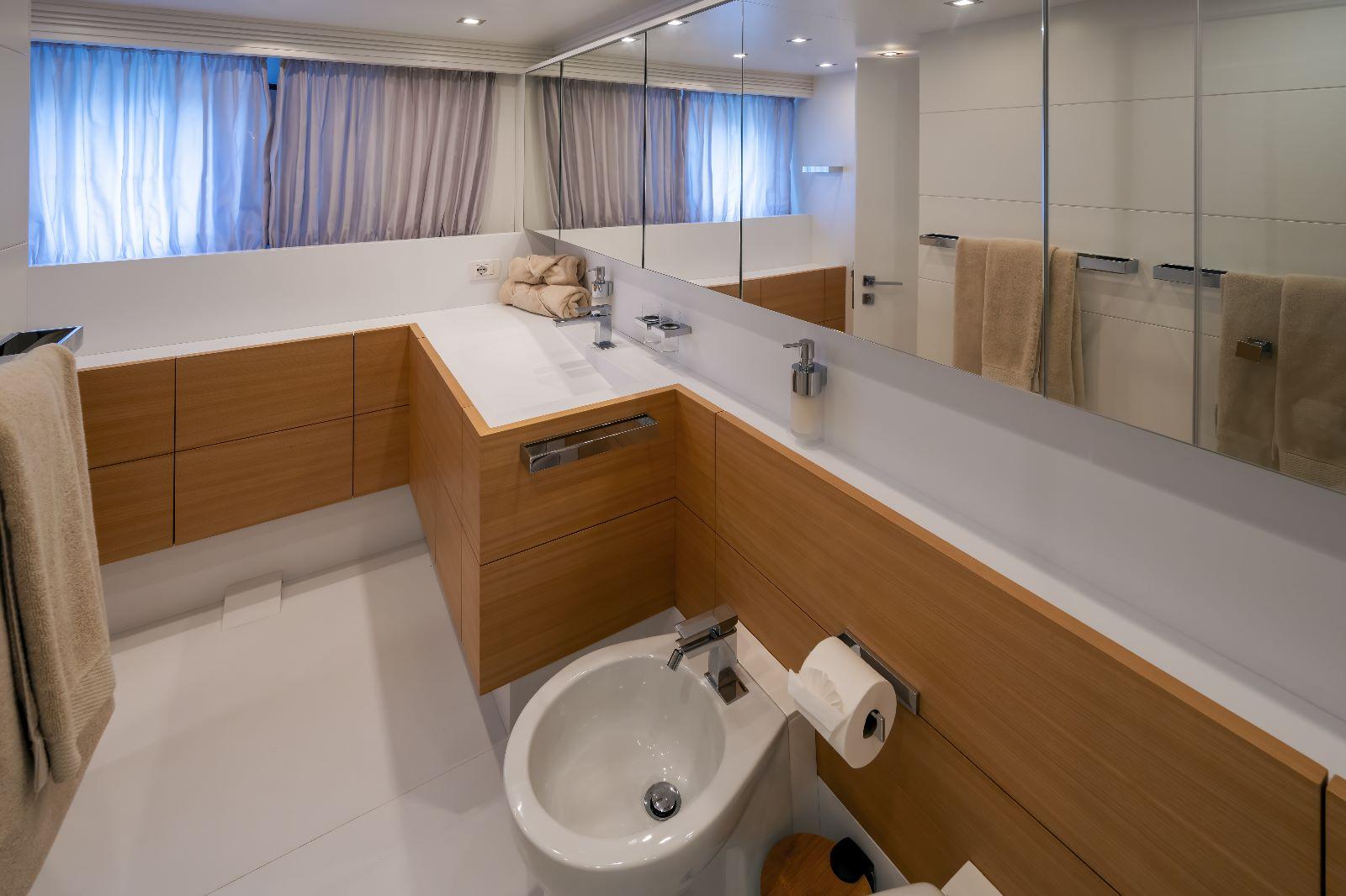 Luxurious bathroom in 2011 Maiora 27 yacht with modern fixtures and wooden cabinetry.