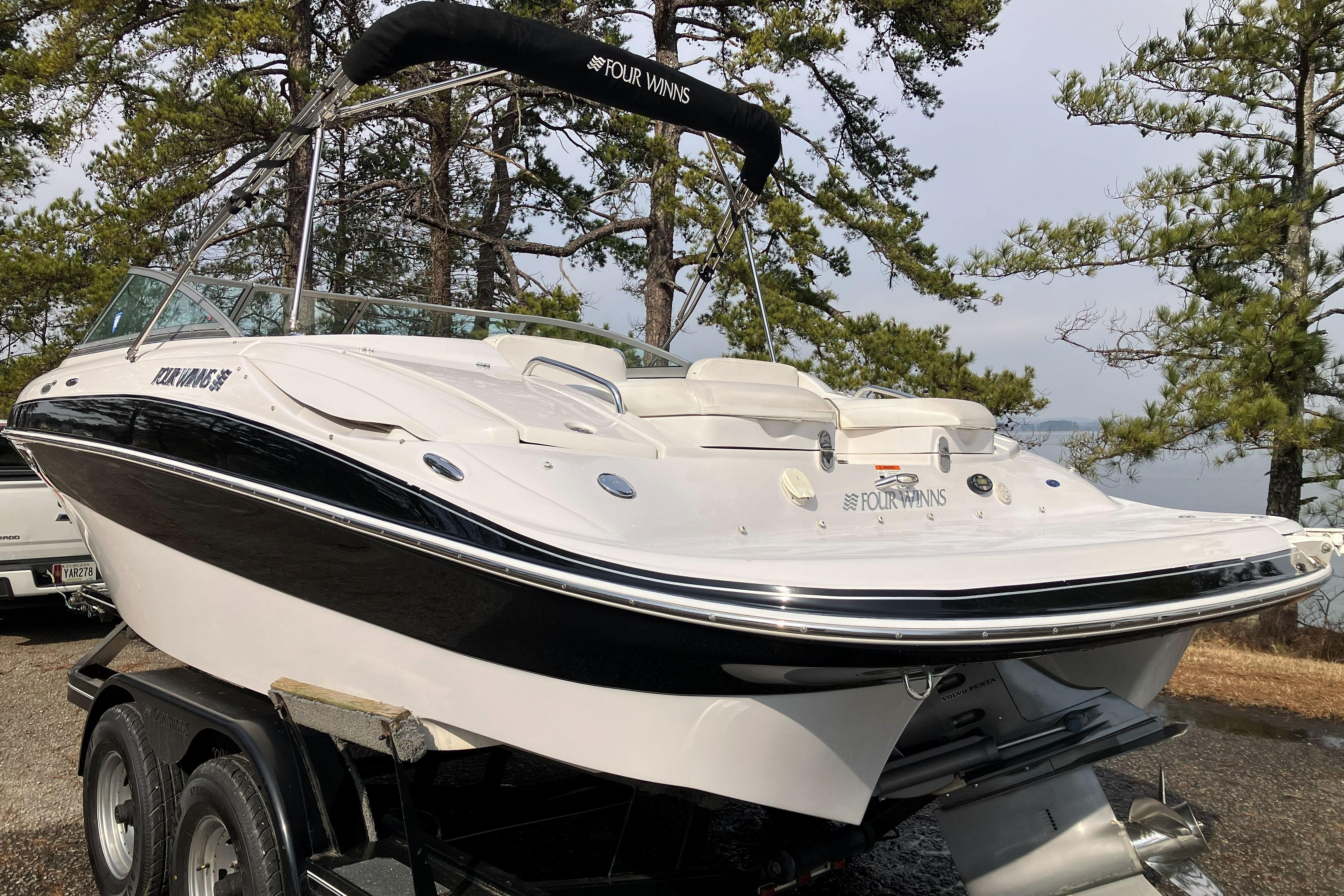 2006 Four Winns 240 Horizon boat on trailer, surrounded by trees and lake view.