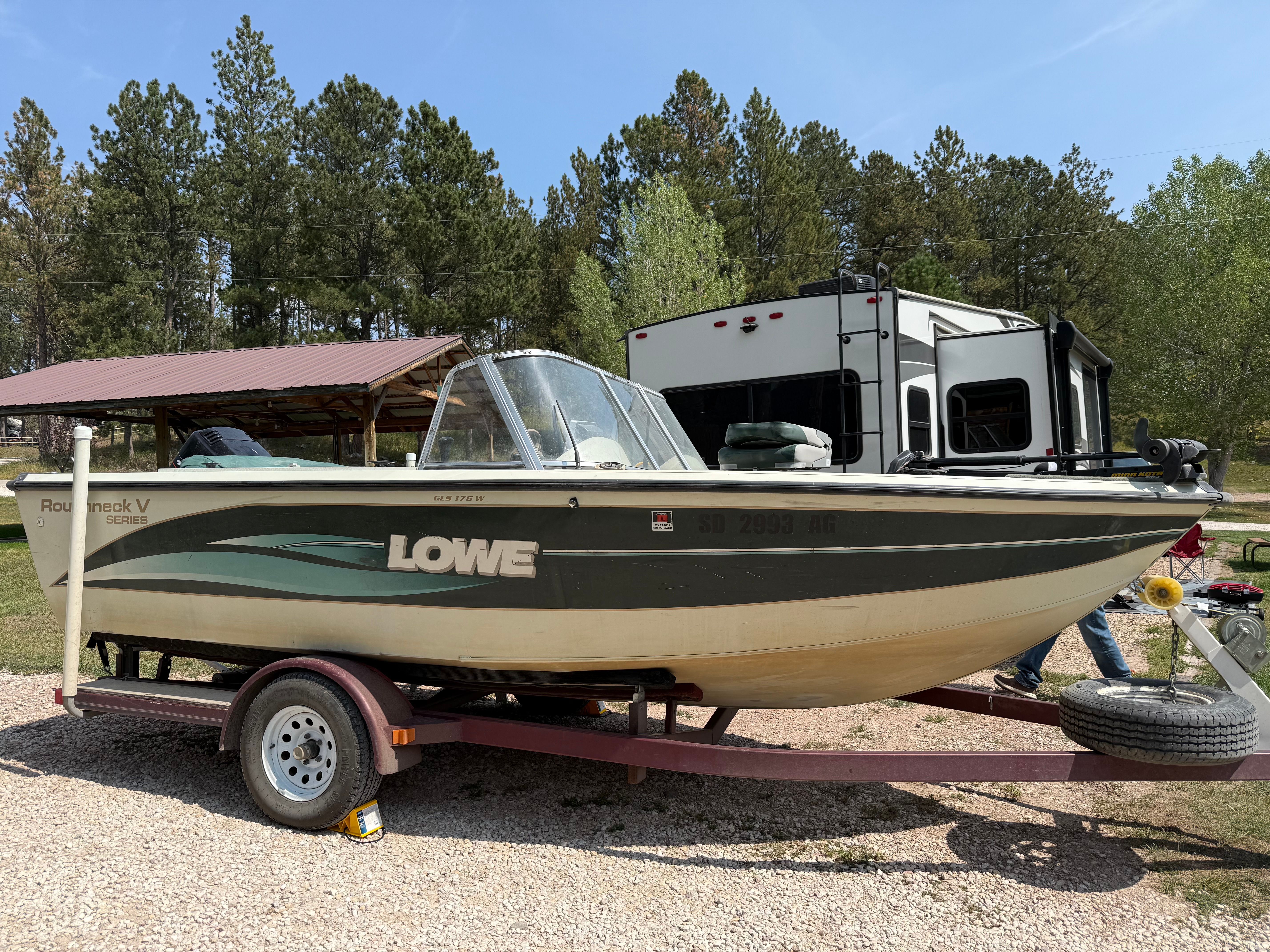 1999 Lowe Roughneck boat on trailer parked outdoors.