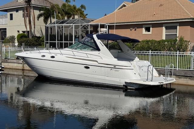 1999 Cruisers 3870 Express yacht docked by waterfront homes.