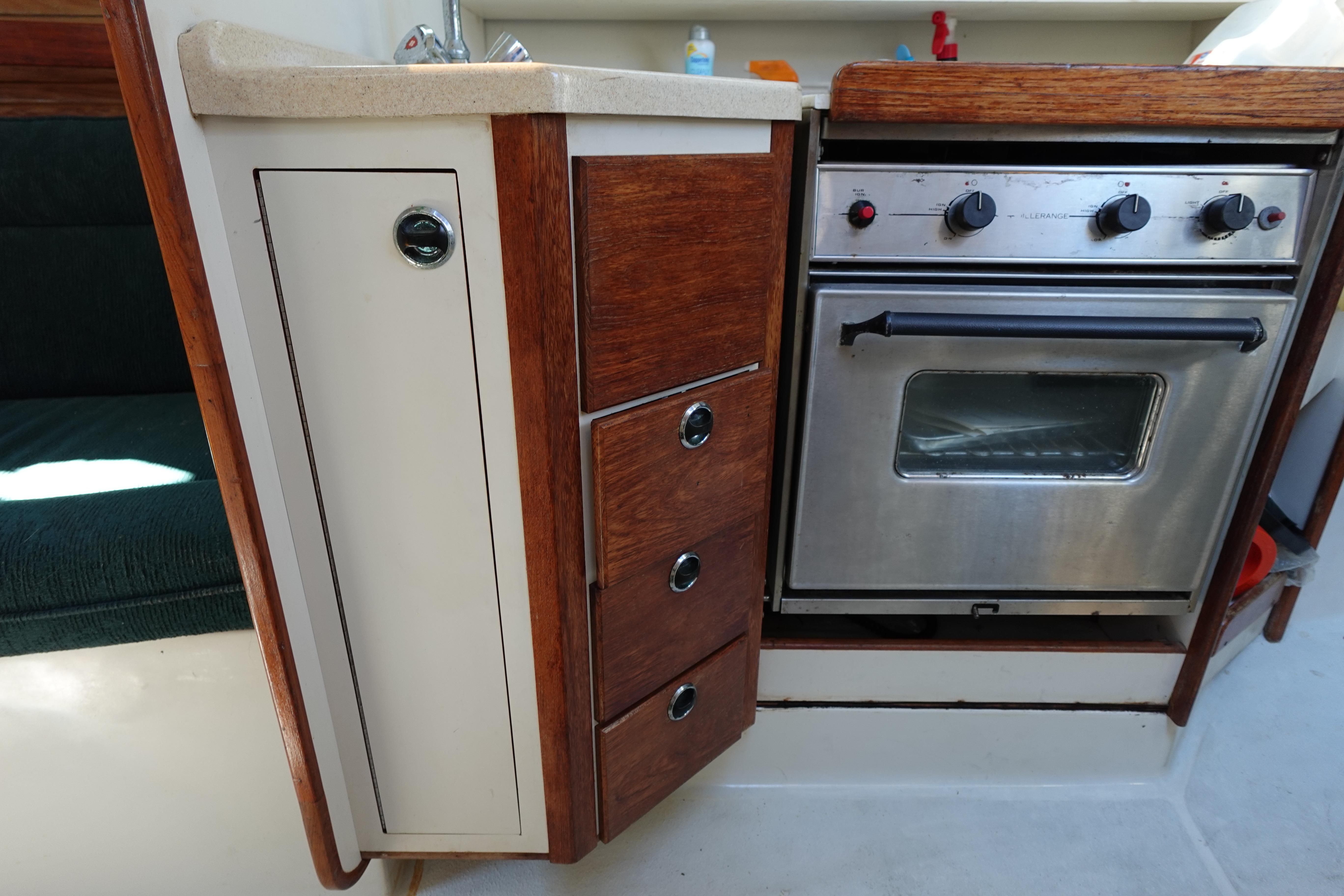 1997 Catalina 28 yacht kitchen with stove, wooden cabinets, and sink.