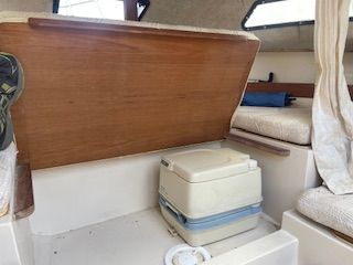 Interior of a 1986 Wellcraft Starwind 19 with a portable toilet and seating area.