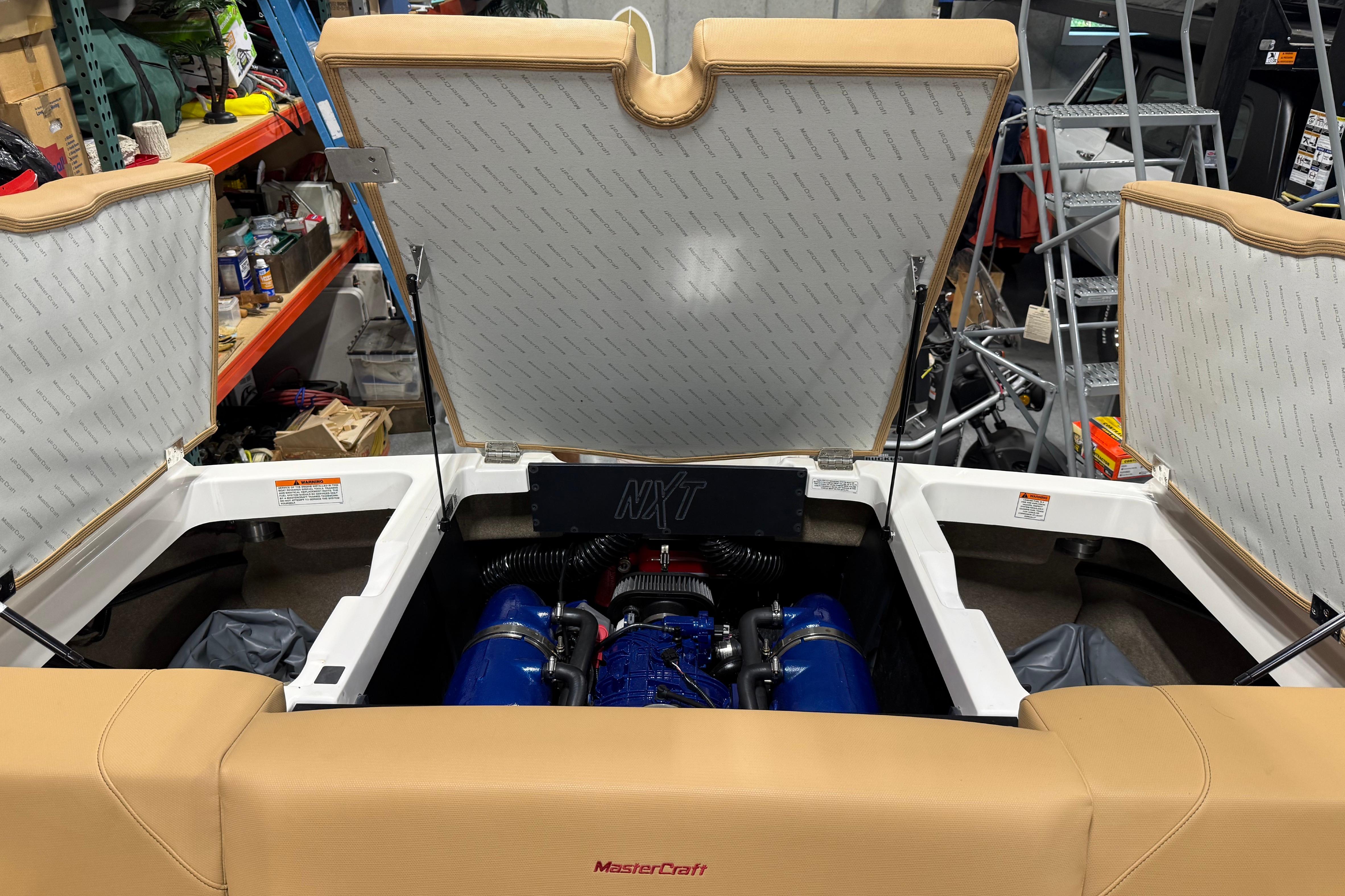 2022 MasterCraft NXT24 boat engine compartment with open hatches in a workshop setting.
