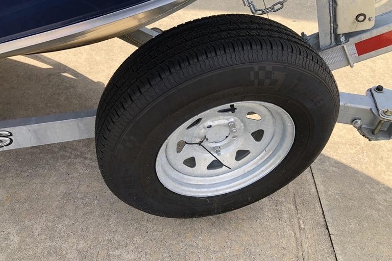 Trailer wheel of 2023 Alumaweld Talon 18 boat on concrete surface.