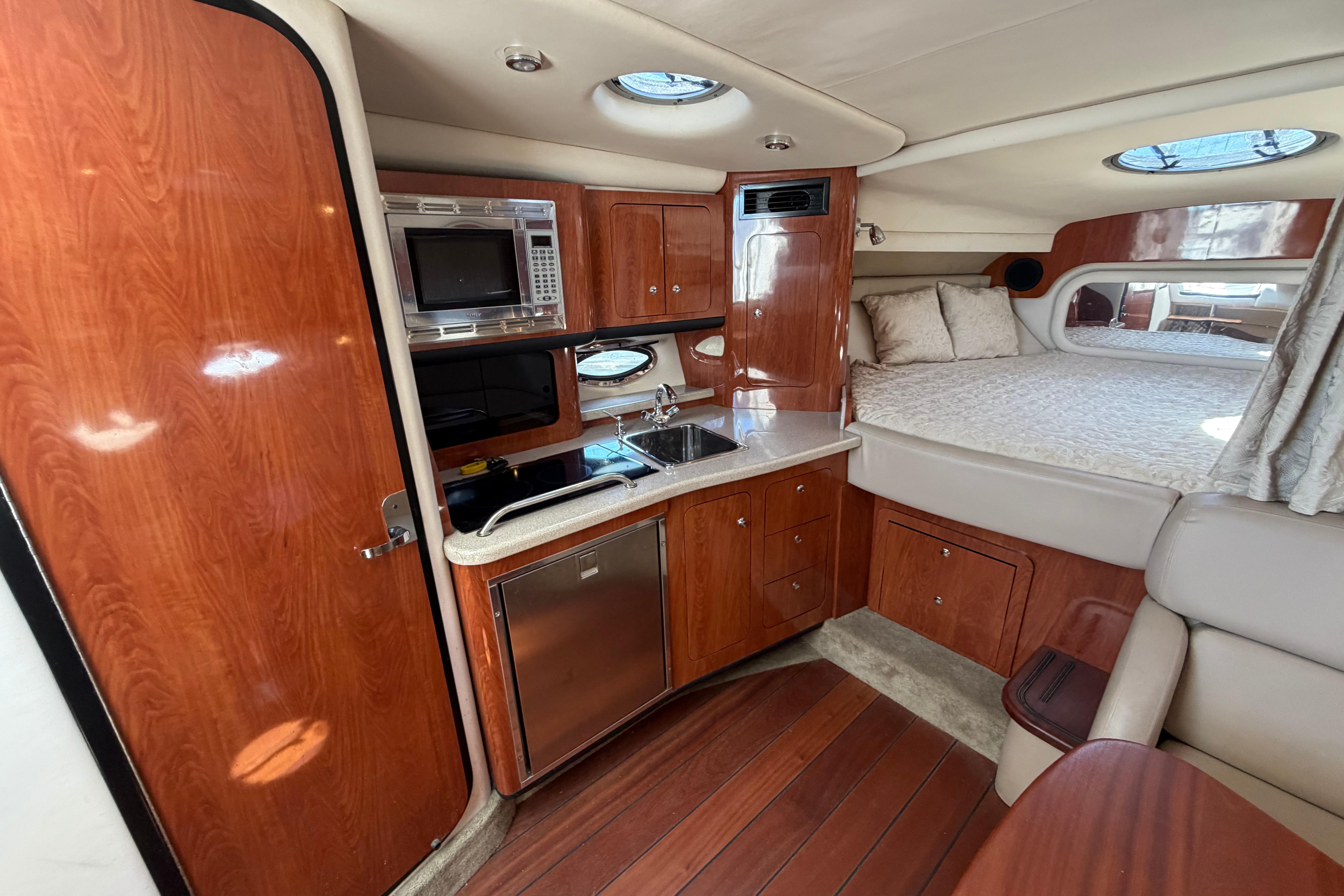 Luxurious 2008 Crownline 340 CR cabin interior with kitchenette and cozy sleeping area.