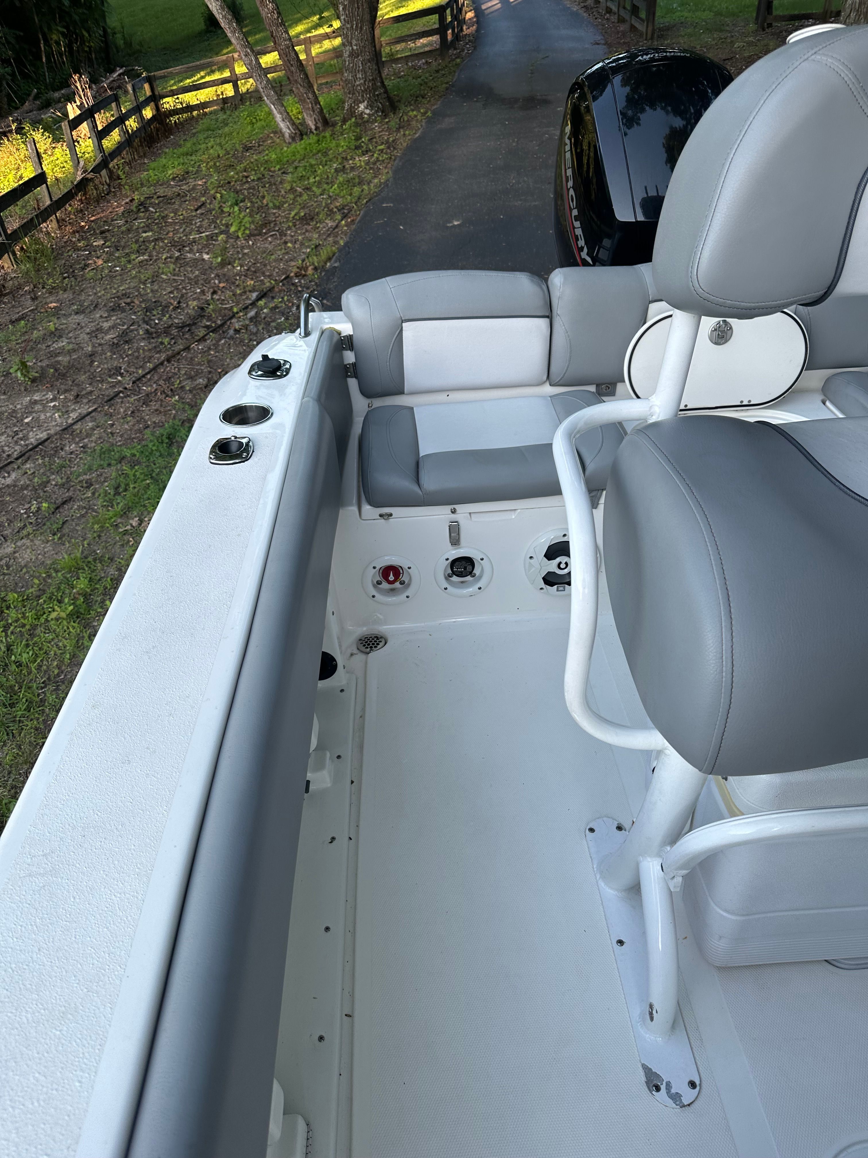 The image shows the cockpit of a NauticStar 2102 Legacy boat with gray seats and fishing rod holders.