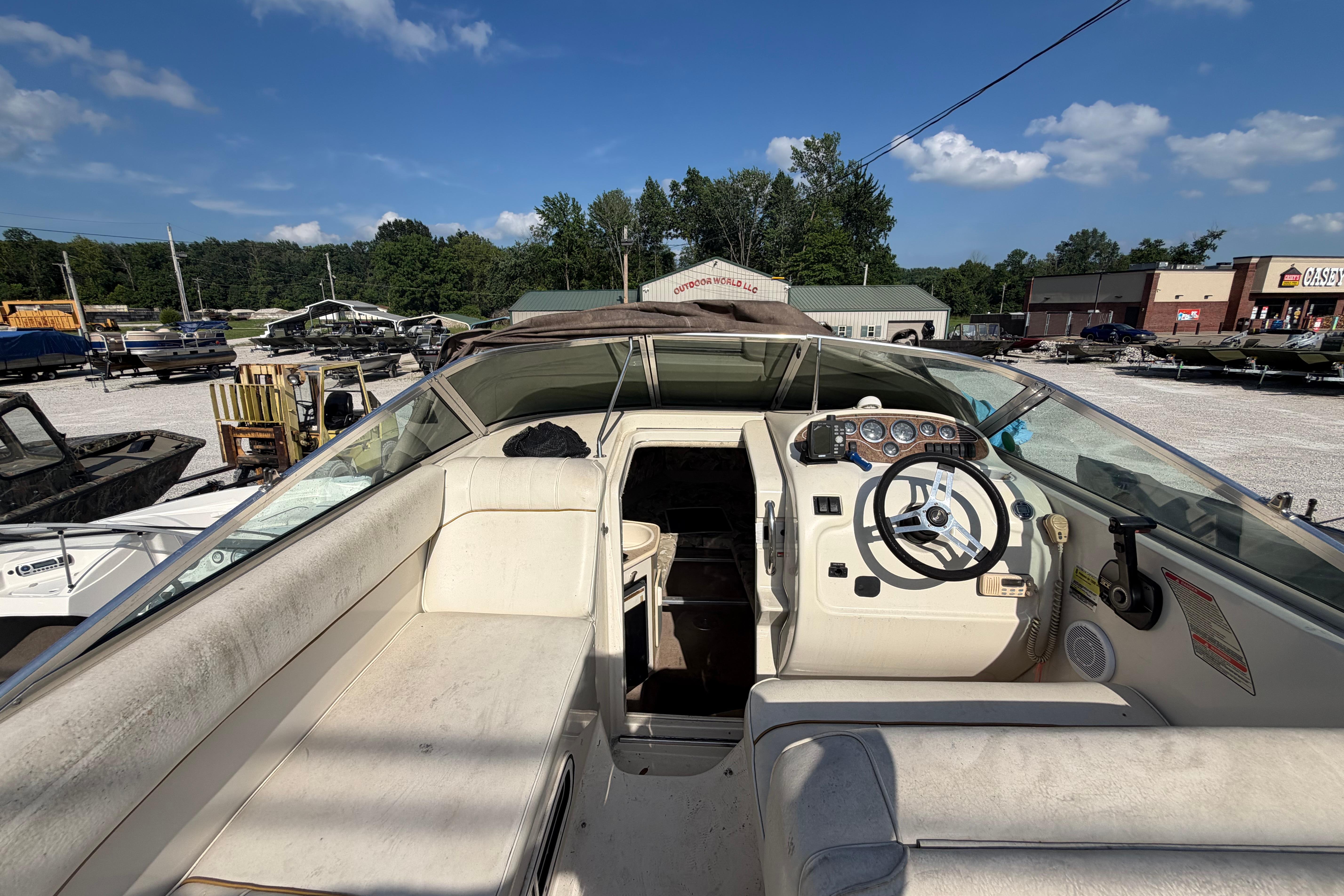 1999 Sea Ray 240 Sundancer boat interior with steering wheel and seating, parked outdoors.