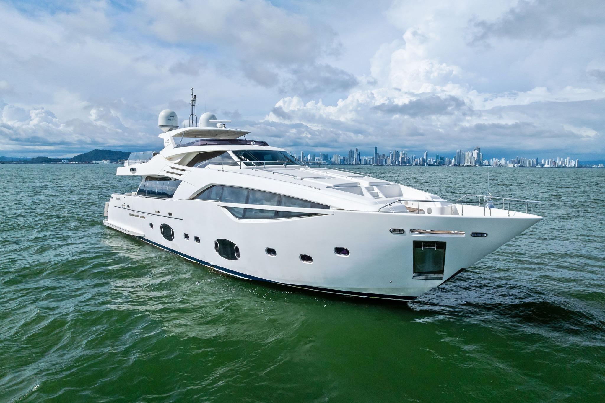 Luxurious 2014 Custom Line 100 yacht cruising on open water with city skyline backdrop.
