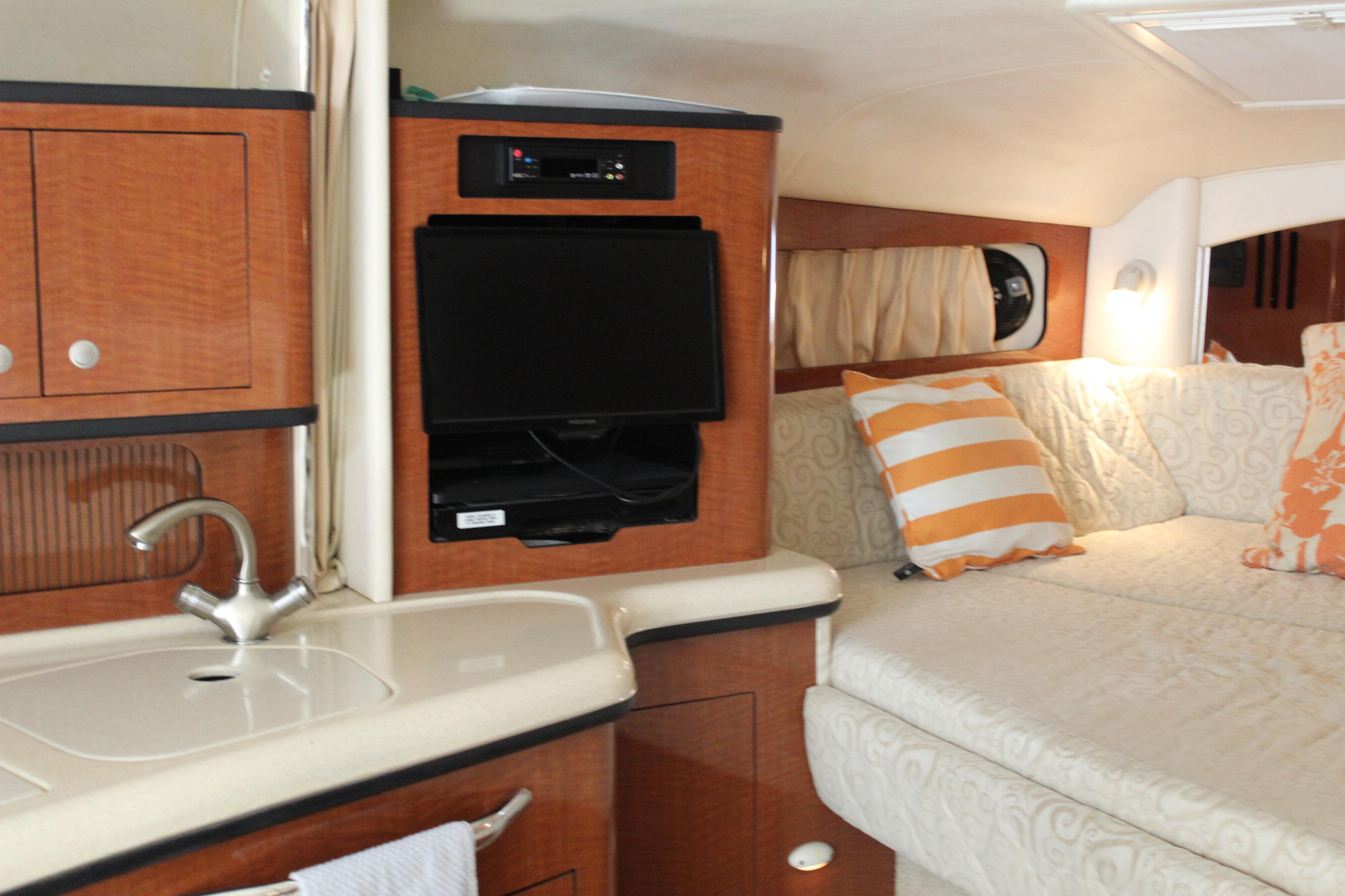 Interior of 2005 Sea Ray 300 Sundancer with cozy seating, TV, and kitchenette.