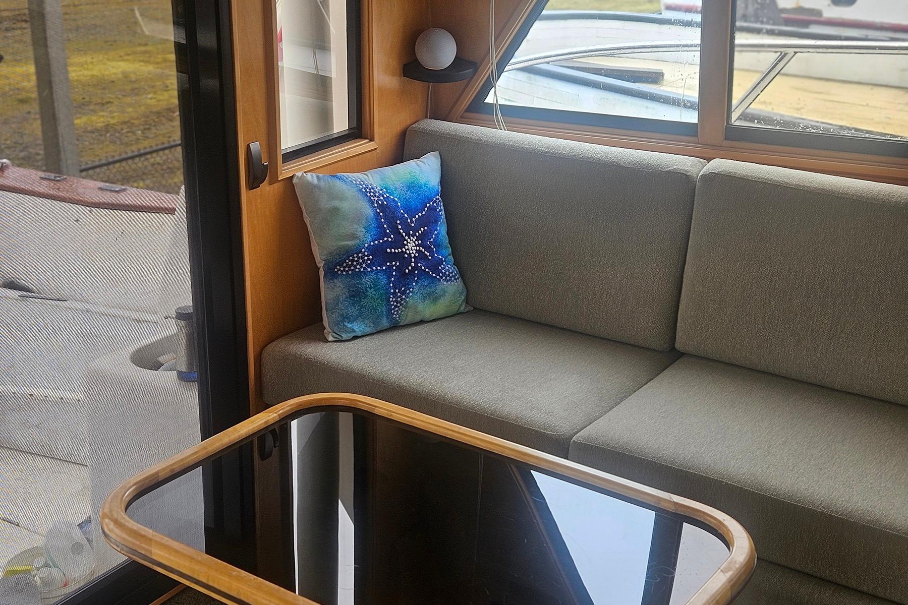 Cozy boat interior with gray sofa, starfish pillow, and wooden table, Symbol 55, 1995.