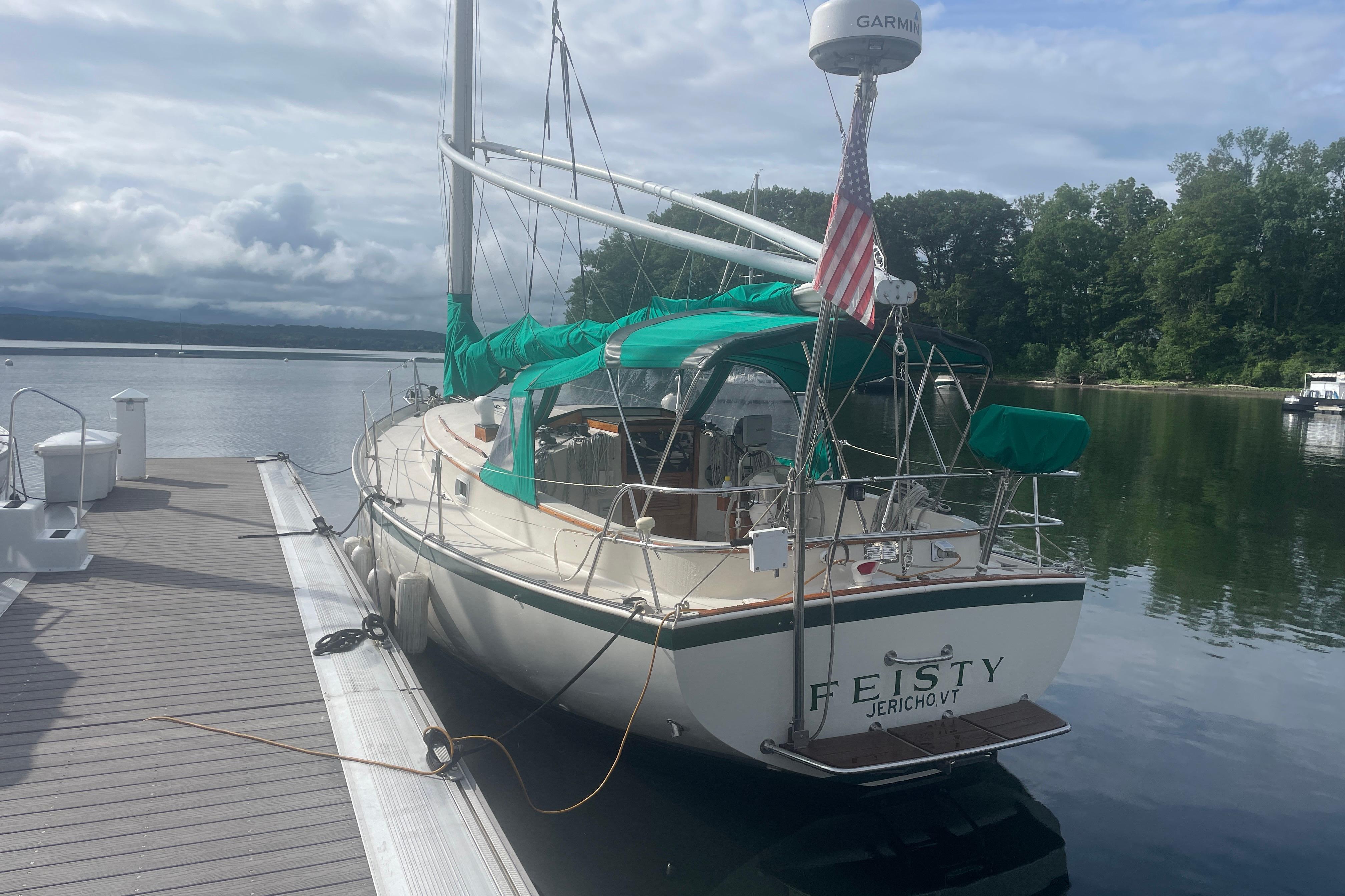 1981 Nonsuch 30 Classic sailboat docked on a calm lake with green canopy.