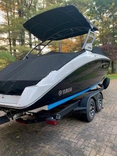 A 2021 Yamaha 252SD boat on a trailer, covered with a black tarp.