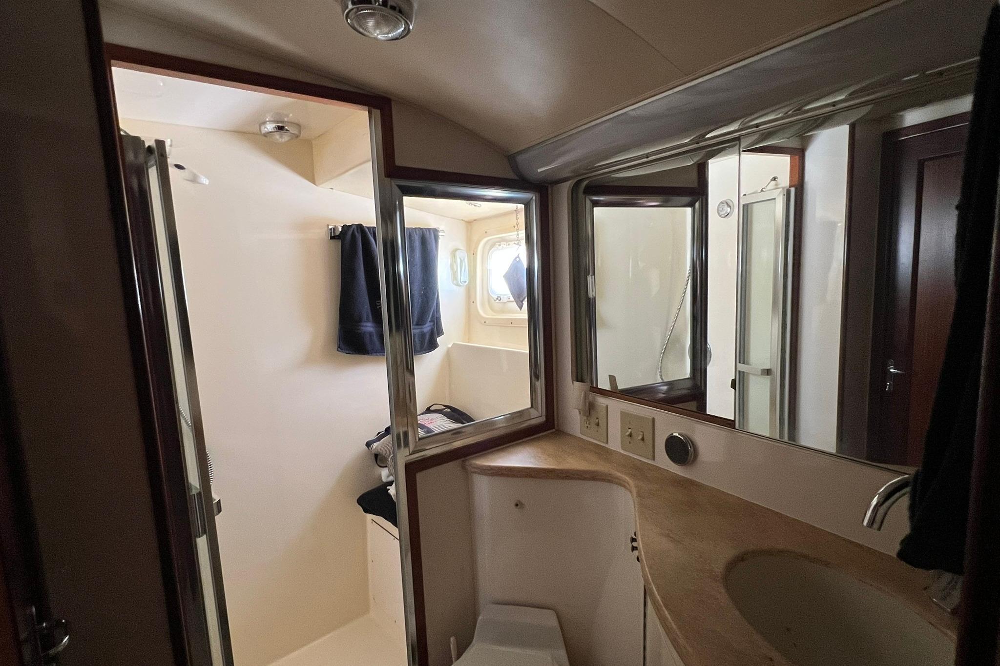Bathroom interior of 1990 Hatteras 41 Convertible yacht, featuring sink, mirror, and shower.