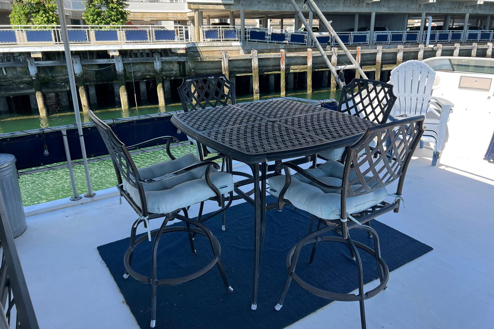 Outdoor seating on 1993 Sumerset houseboat deck with metal chairs and table by the water.