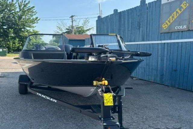 2026 Tracker Pro Guide V-16 WT boat on trailer, parked outdoors near blue fence.