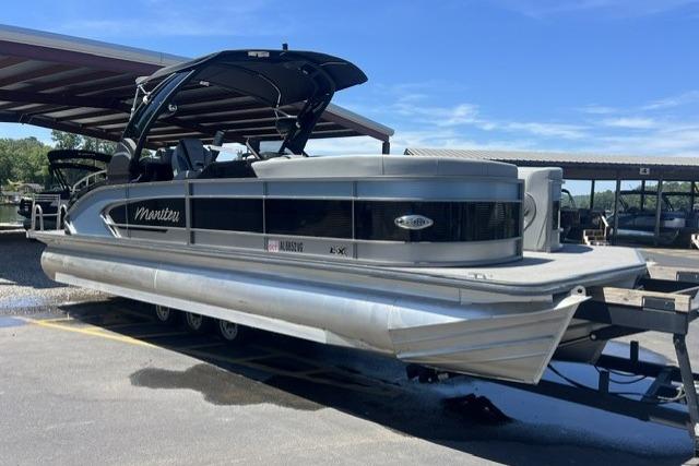 2024 Manitou 25 LX SRW pontoon boat on trailer under a canopy.