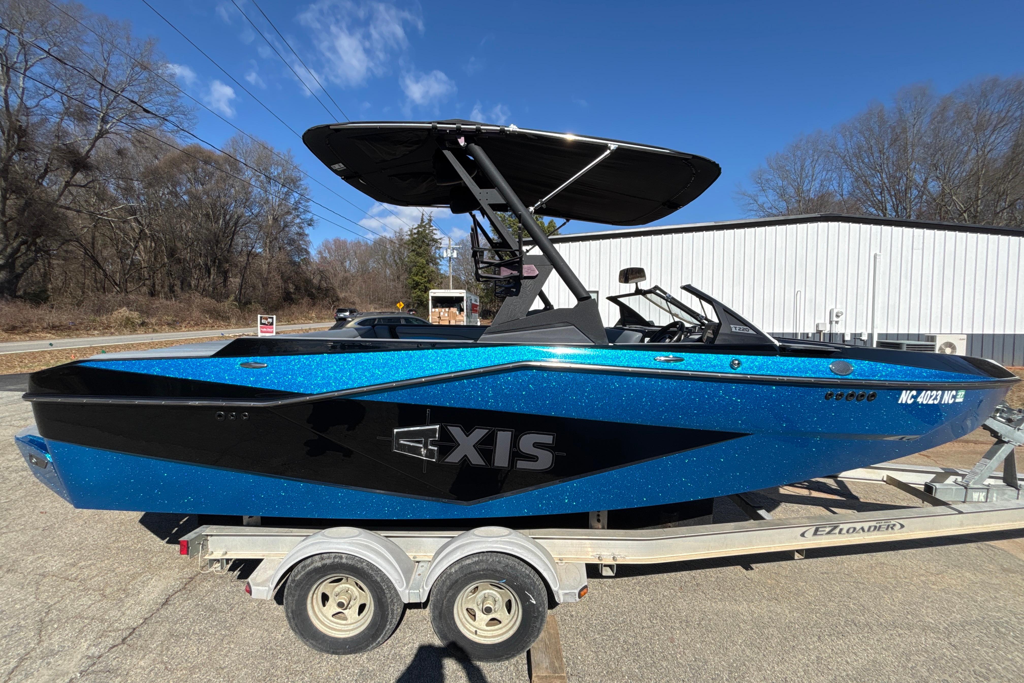2023 Axis T220 boat in blue and black on a trailer, parked outdoors.