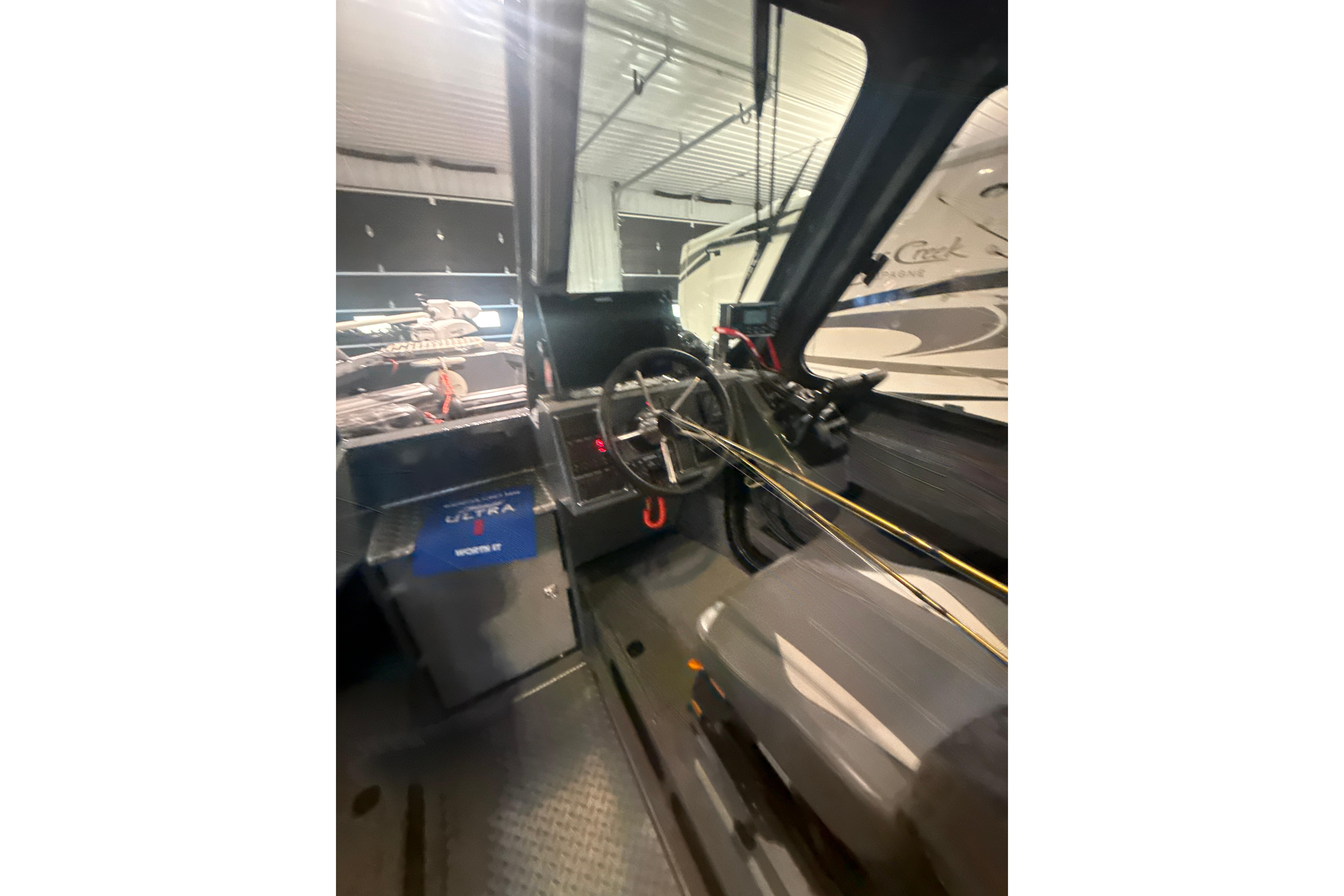 Interior view of 2022 Hewescraft 270 Alaskan Hardtop boat, showcasing steering wheel and controls.
