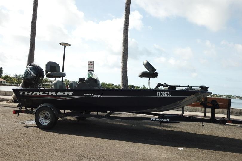 2020 Tracker Pro 170 boat on trailer, parked near waterfront under palm trees.